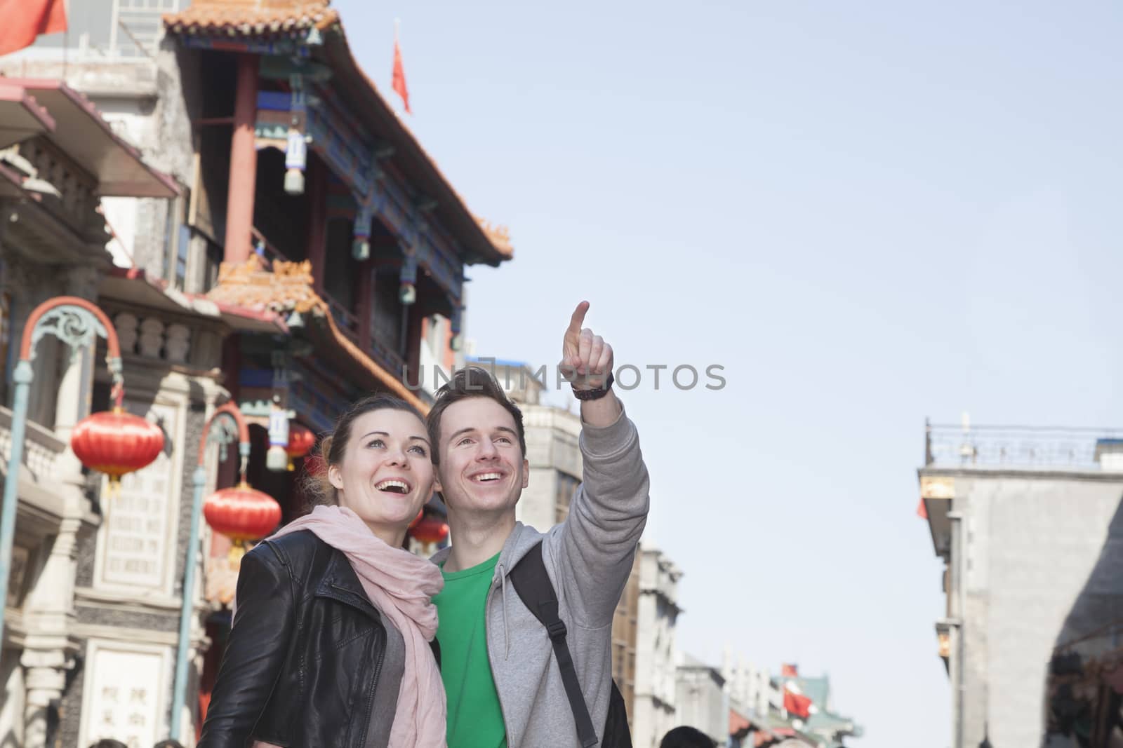 Young couple sightseeing, looking and pointing. by XiXinXing