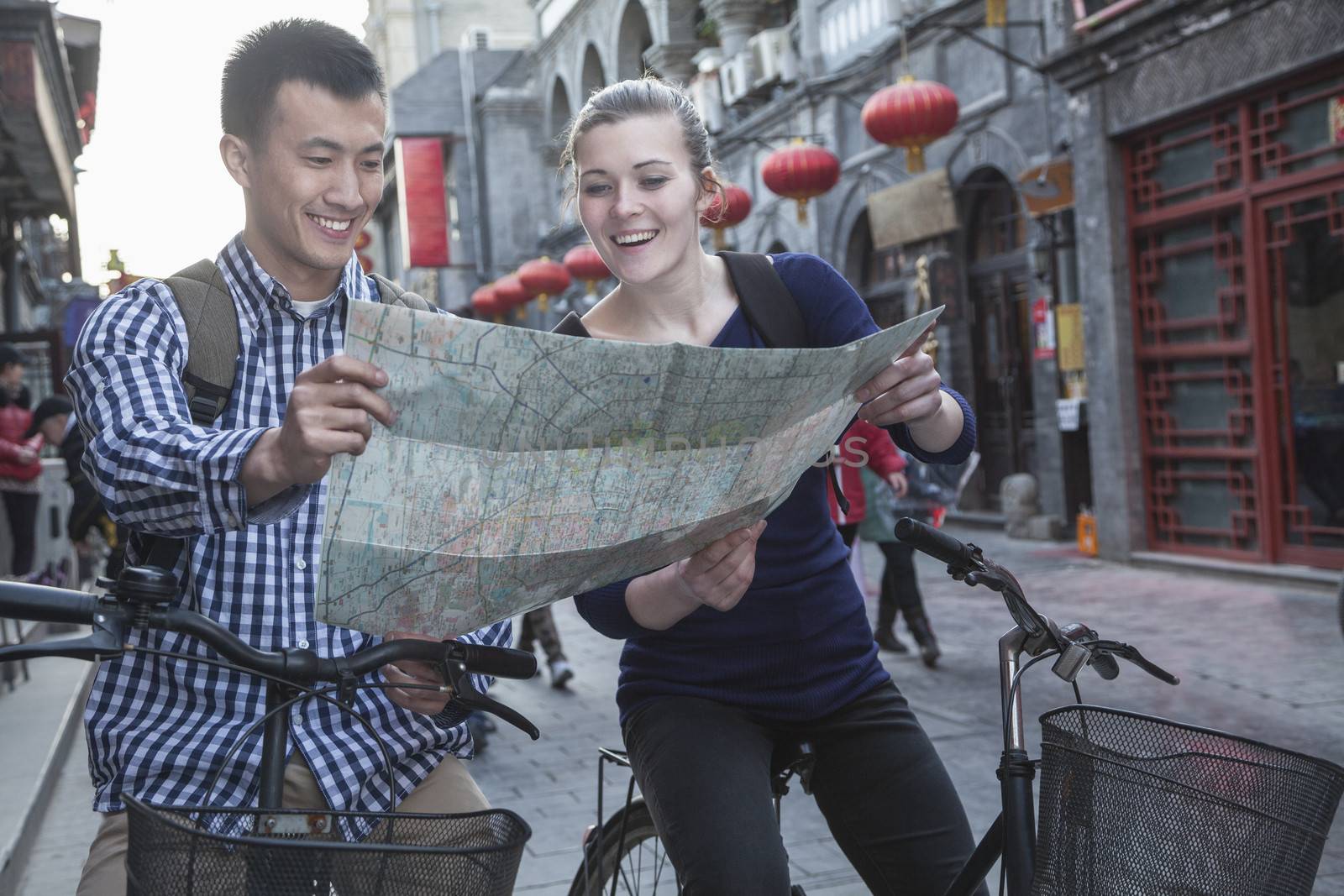 Young man and woman on bicycles, looking at map. by XiXinXing