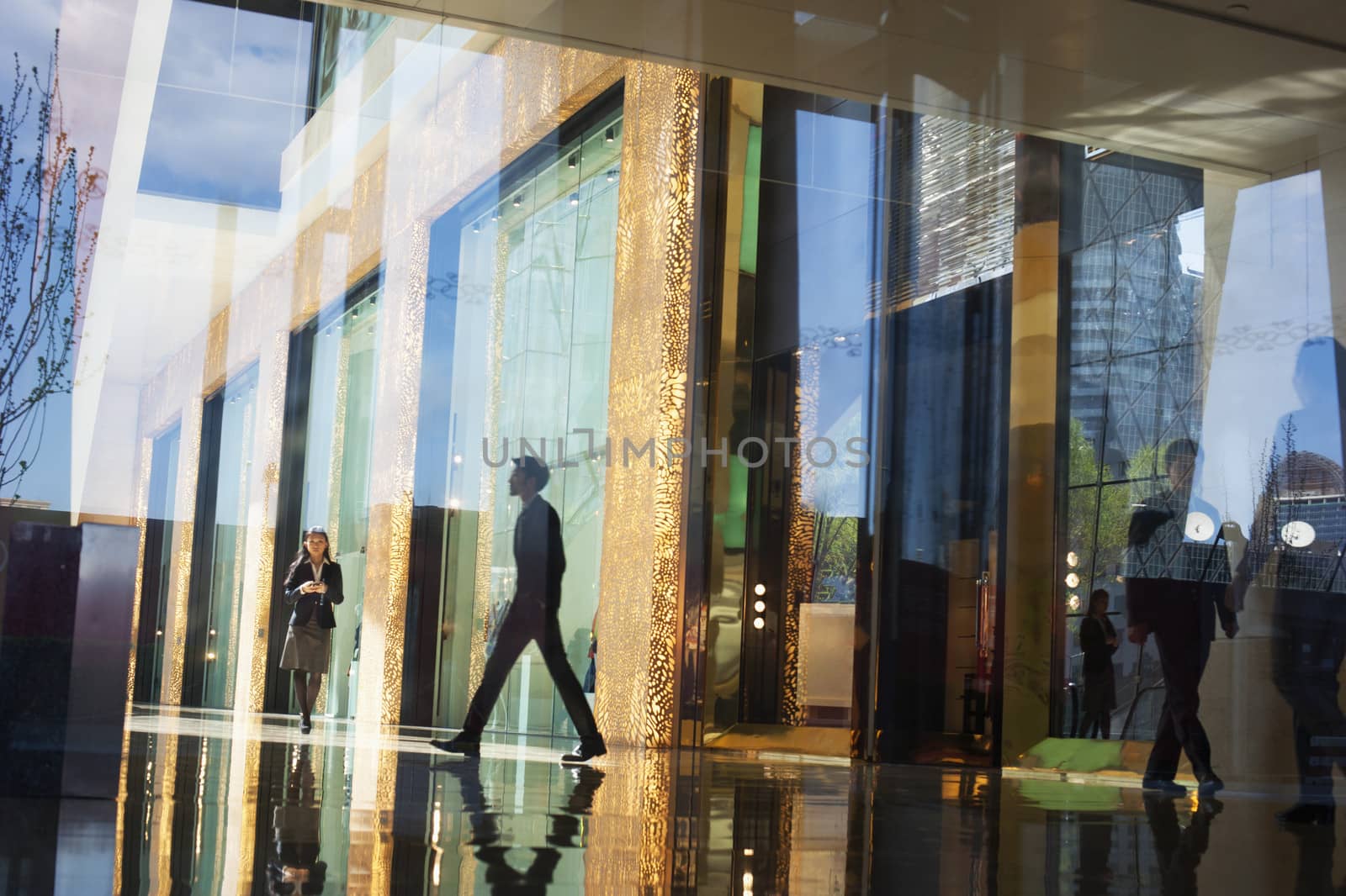 Business People walking through the lobby of an office building on the other side of a glass wall