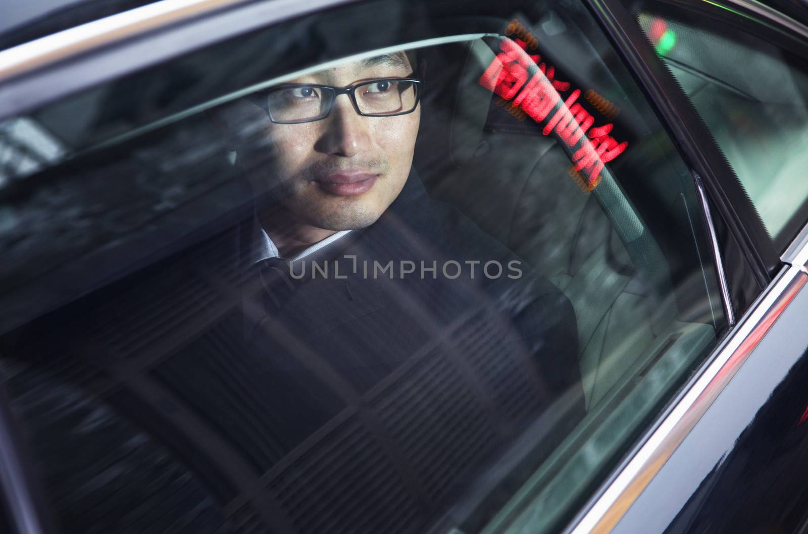 Contemplative businessman looking through car window at the night 