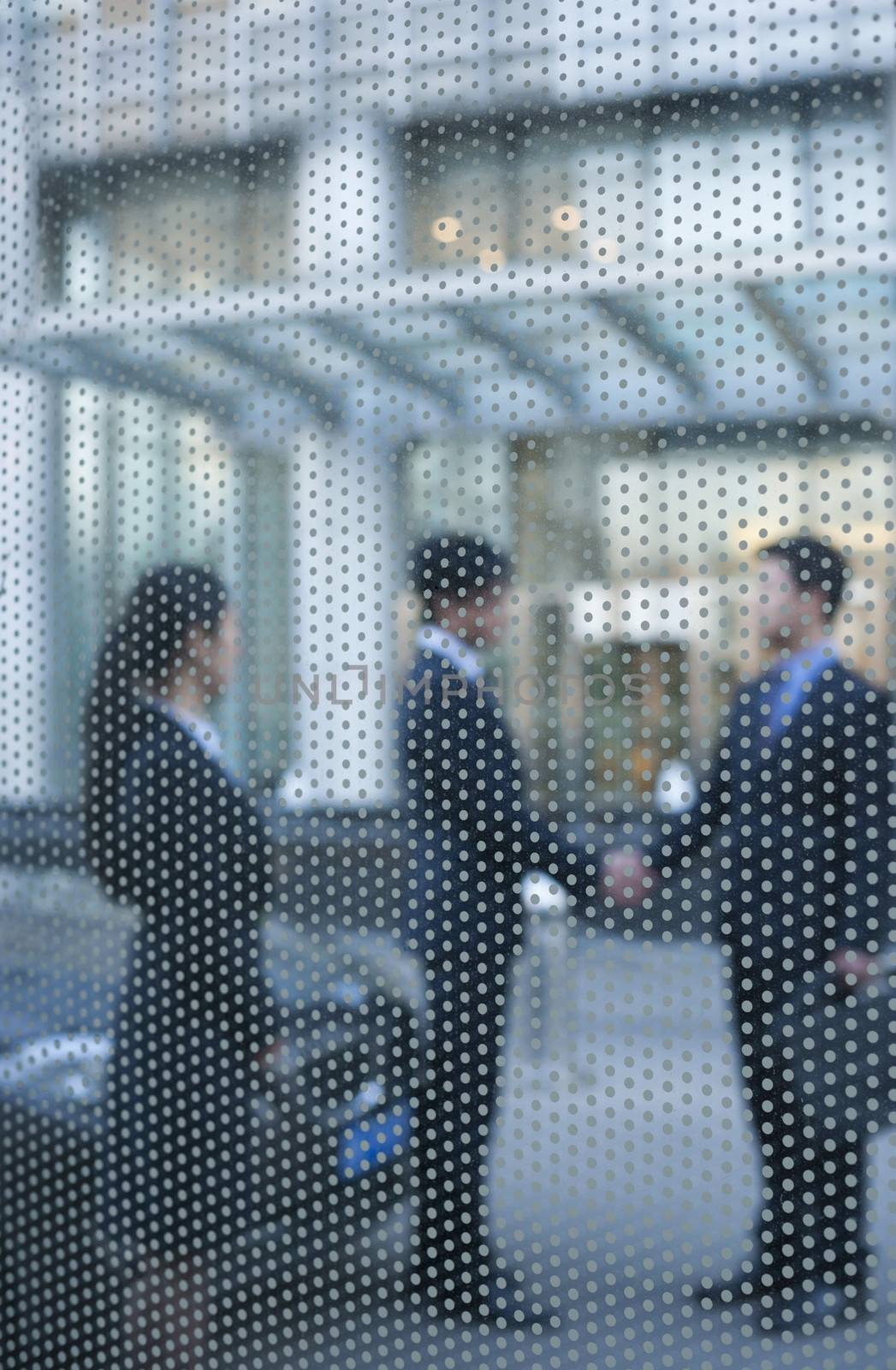 Two businessmen shaking hands outside behind a glass wall by XiXinXing