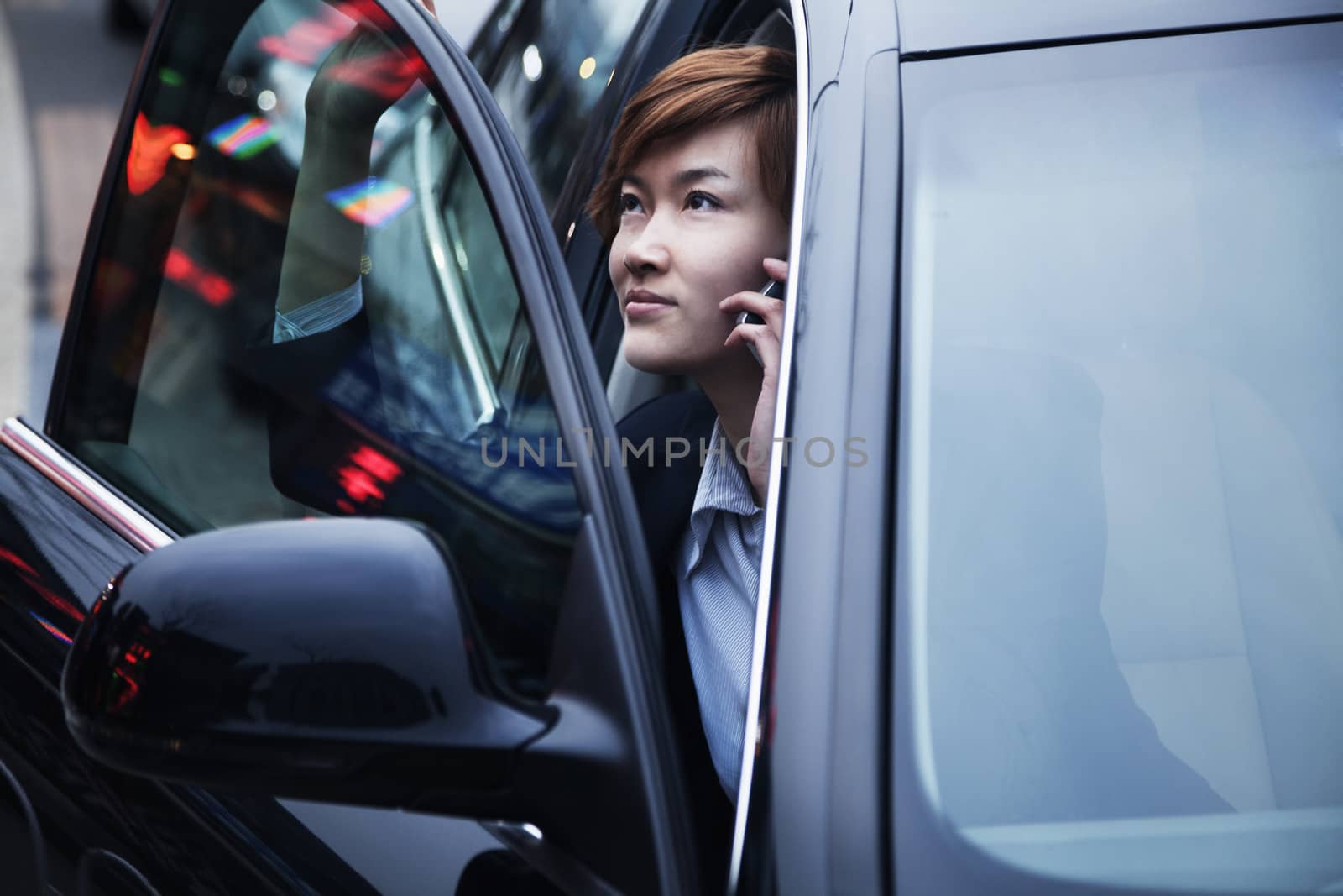 Businesswoman exiting car while on the phone by XiXinXing