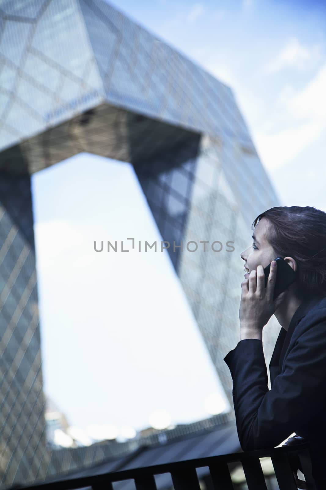 Smiling businesswoman on the phone outside in Beijing looking at the CCTV building