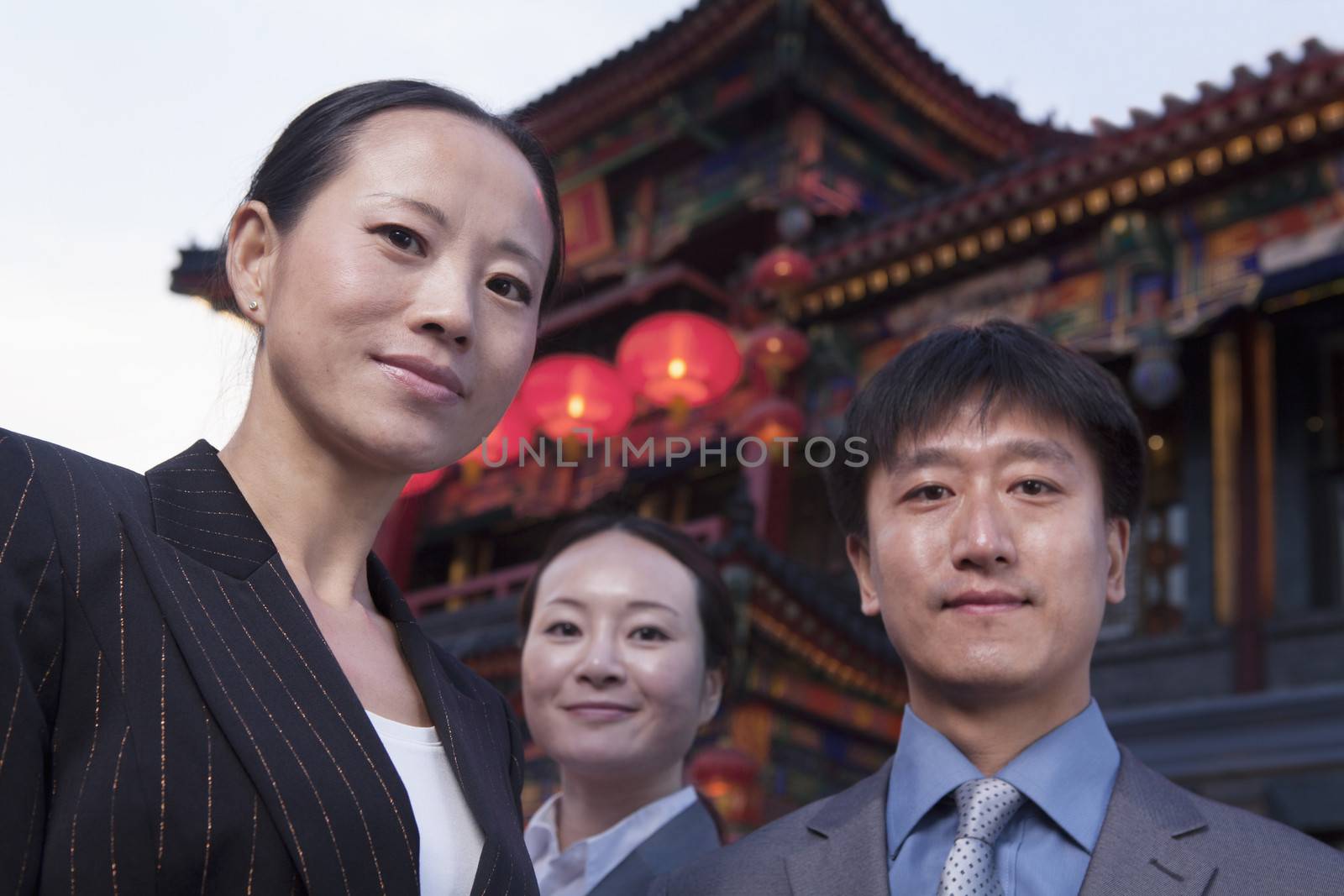 Portrait of three businesspeople with Chinese architecture in background.
