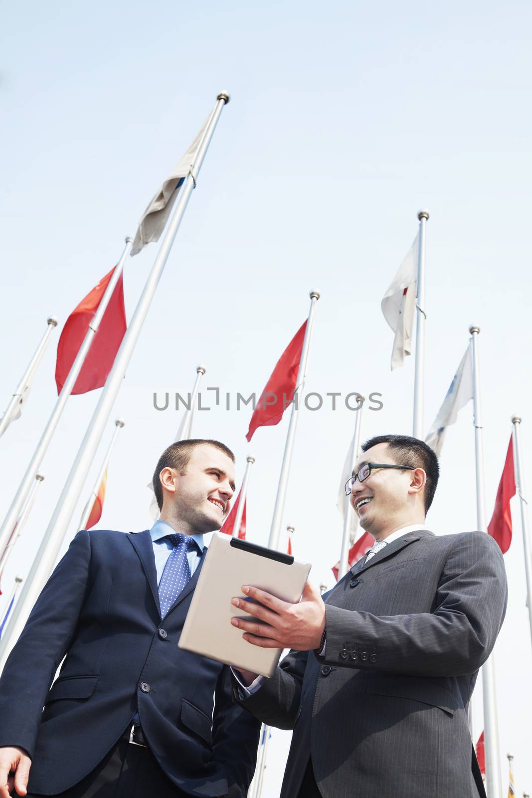 Two smiling business people talking and holding digital tablet
