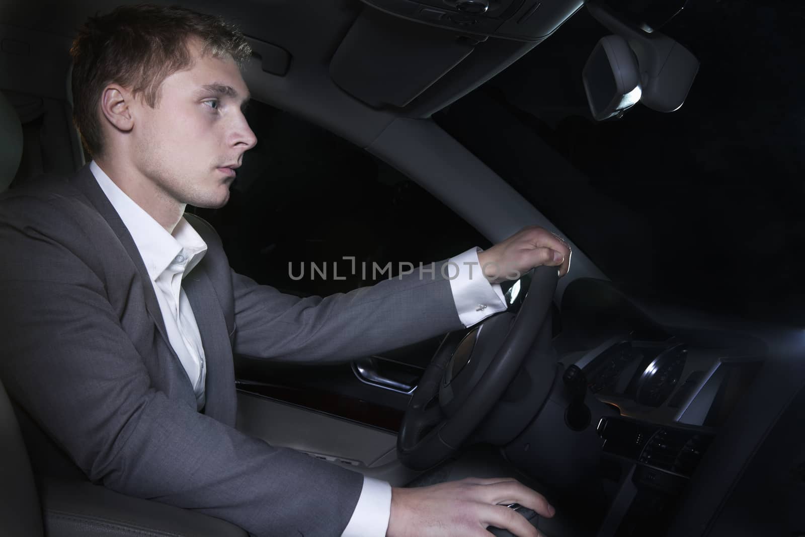 Young well-dressed man in a suit is sitting in his car before going on a night out in Beijing