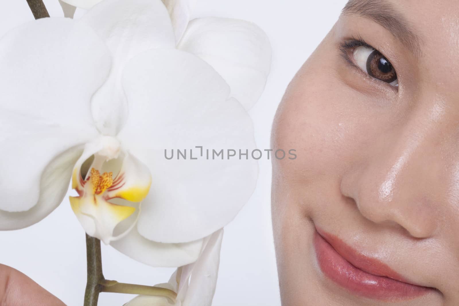 Close up of young woman smiling and a beautiful white flower, half face showing, studio shot by XiXinXing