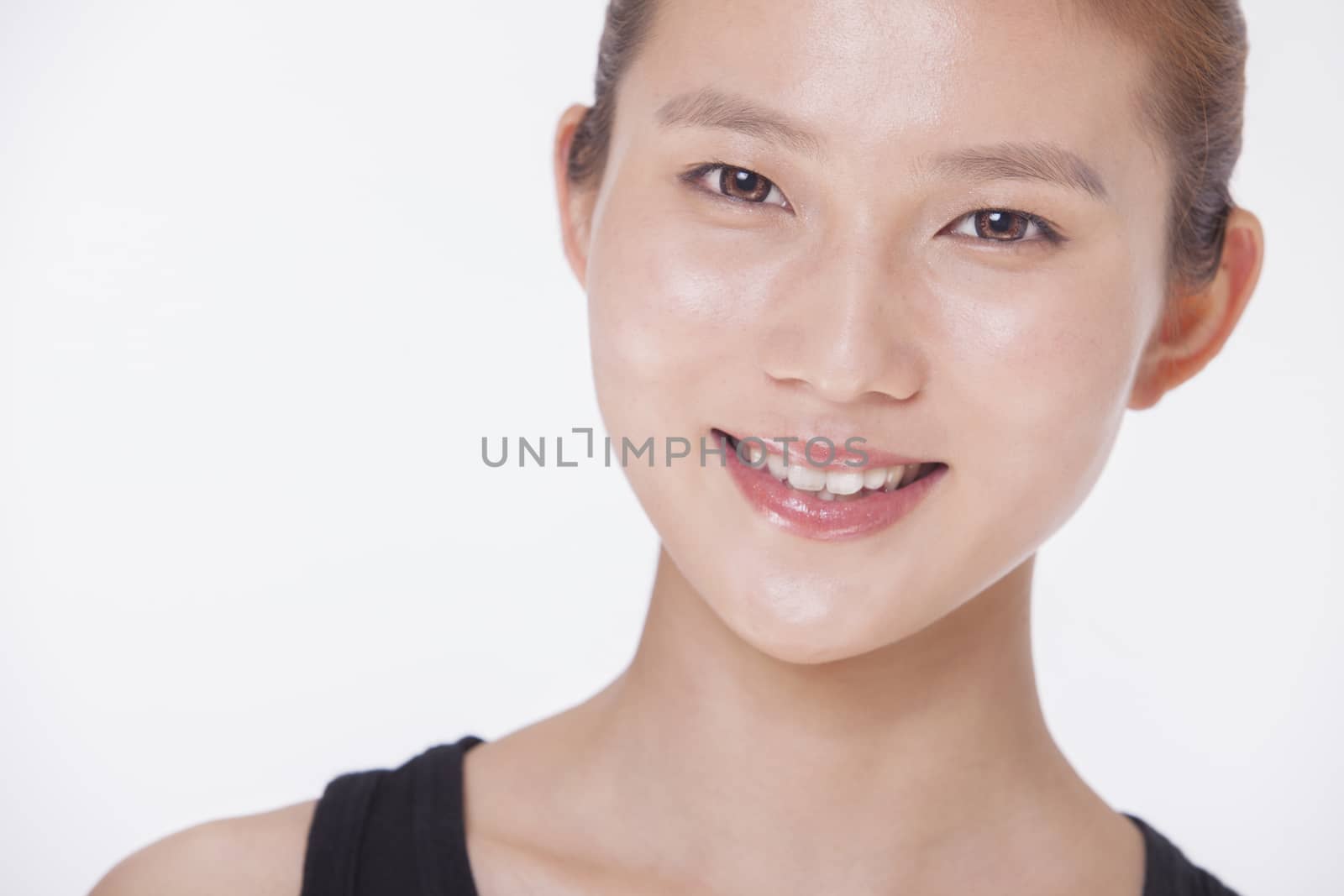 Portrait of smiling beautiful young woman in a black tank top, studio shot 