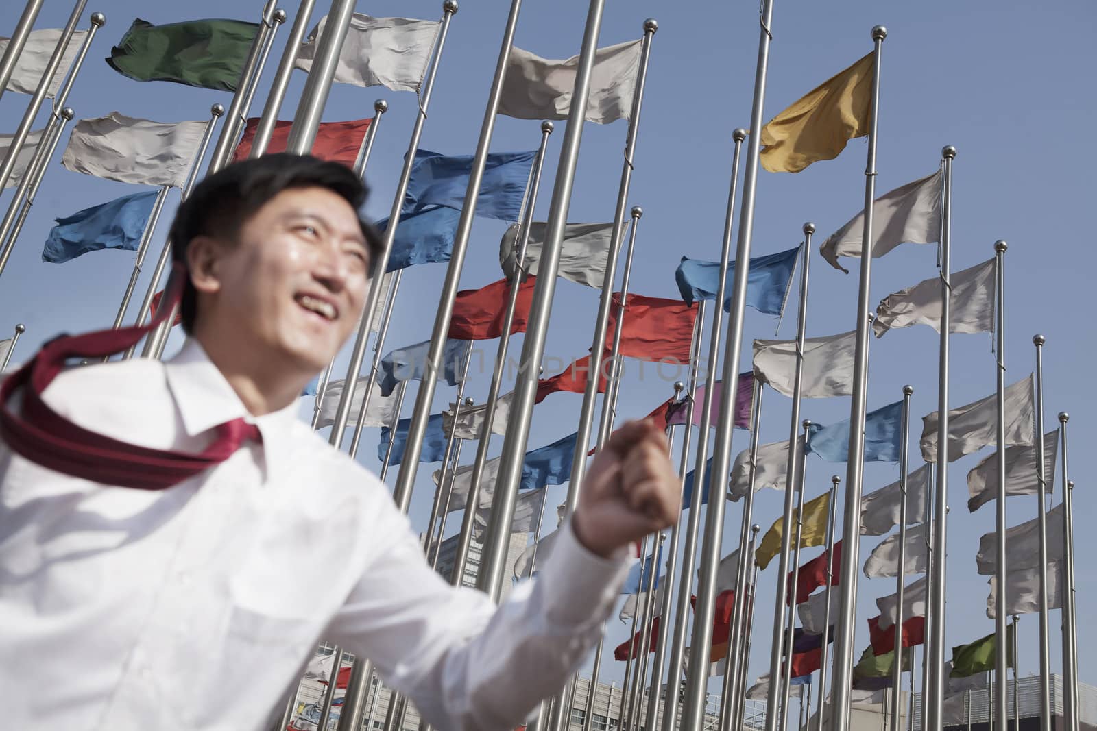 Businessmen running and smiling with flagpoles in background.