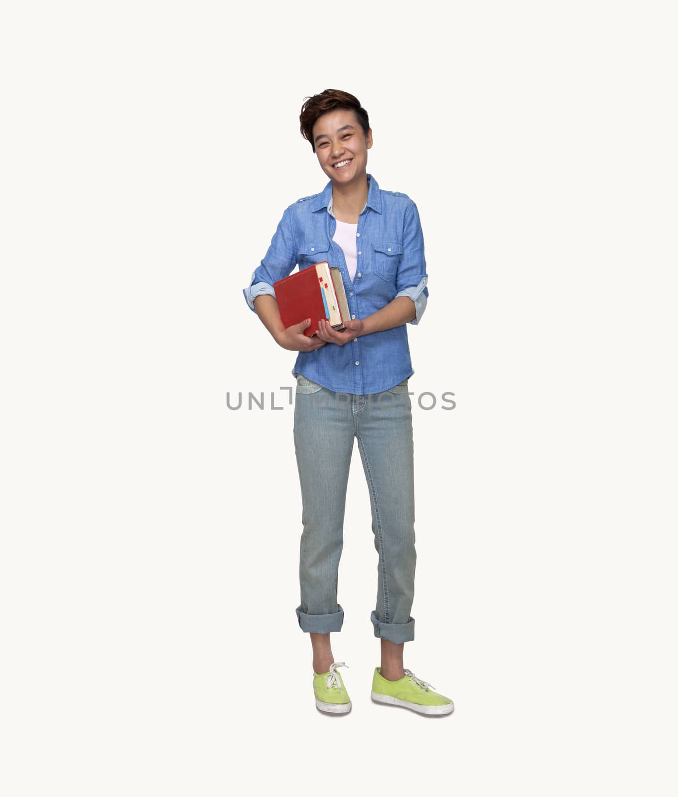 Portrait of smiling young female student holding books, studio shot, full length by XiXinXing