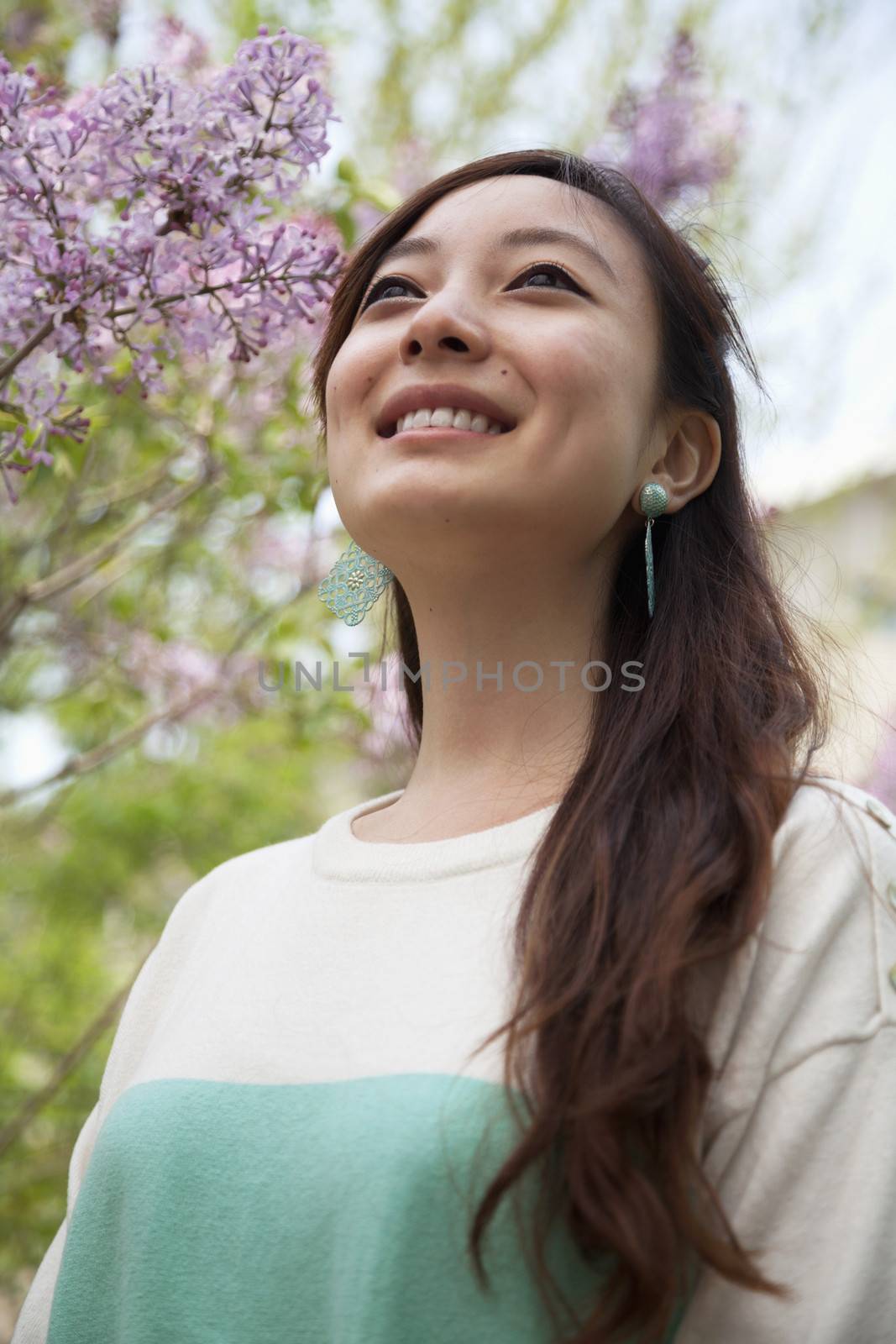 Portrait of smiling young woman with long hair outdoors in the park in springtime