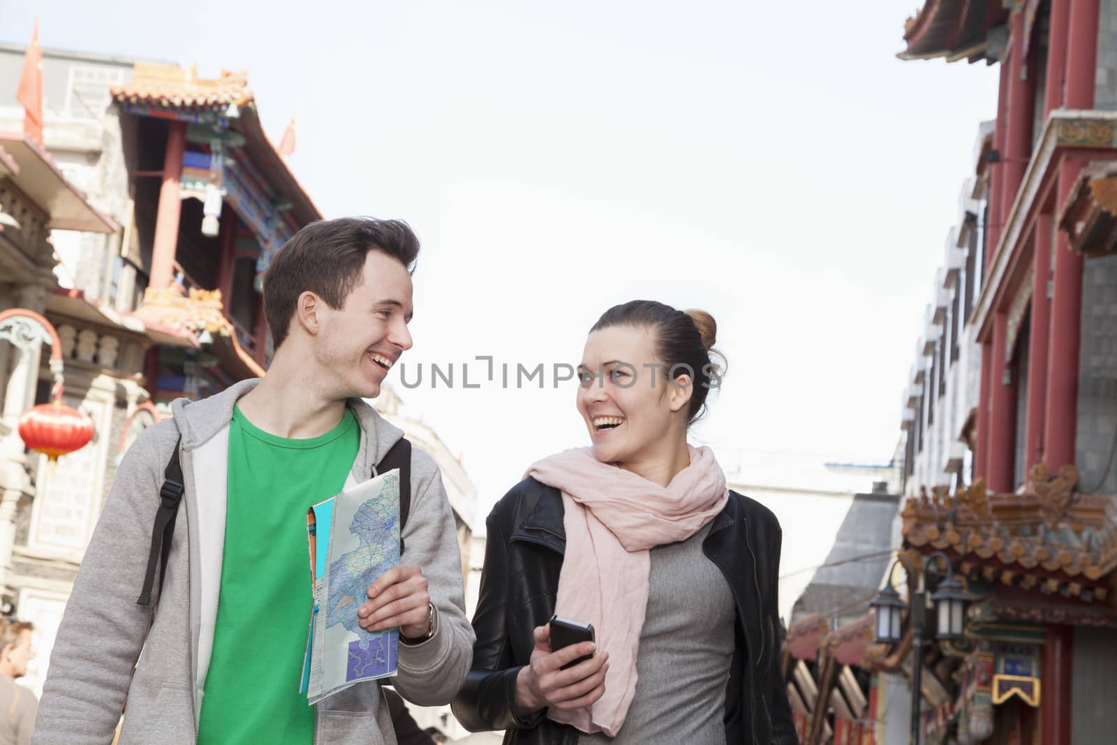 Young couple sightseeing, holding map and mobile phone.