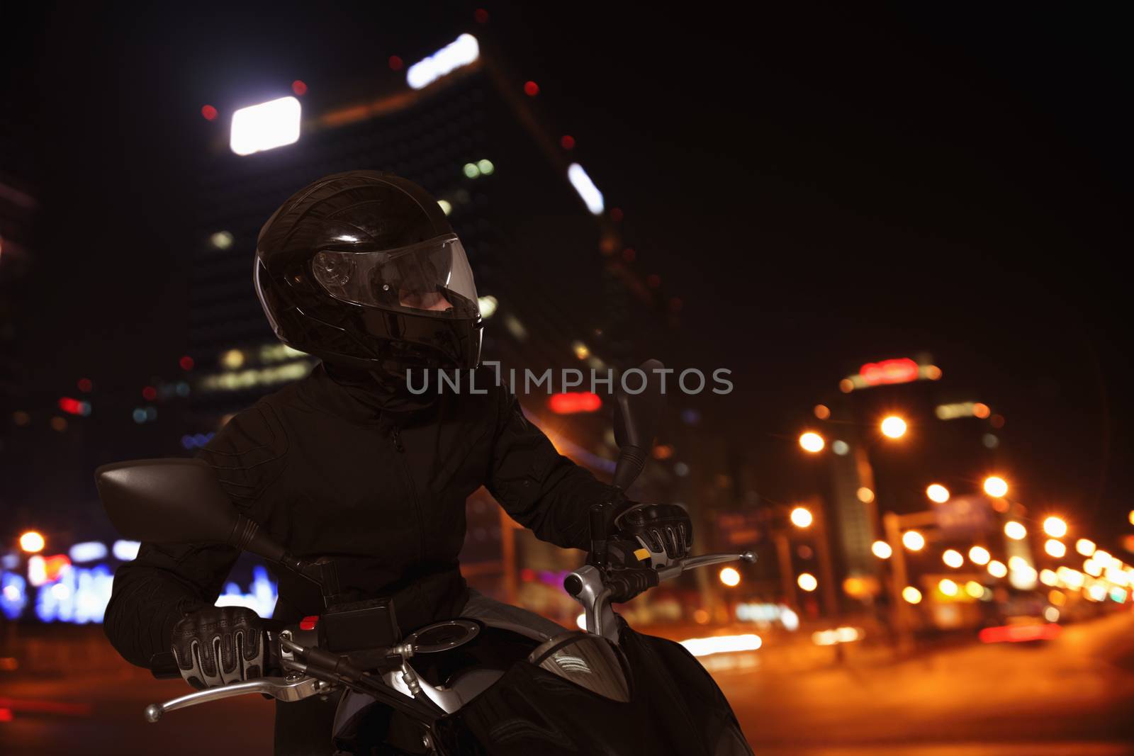 Young Man riding a motorcycle at night through the streets of Beijing