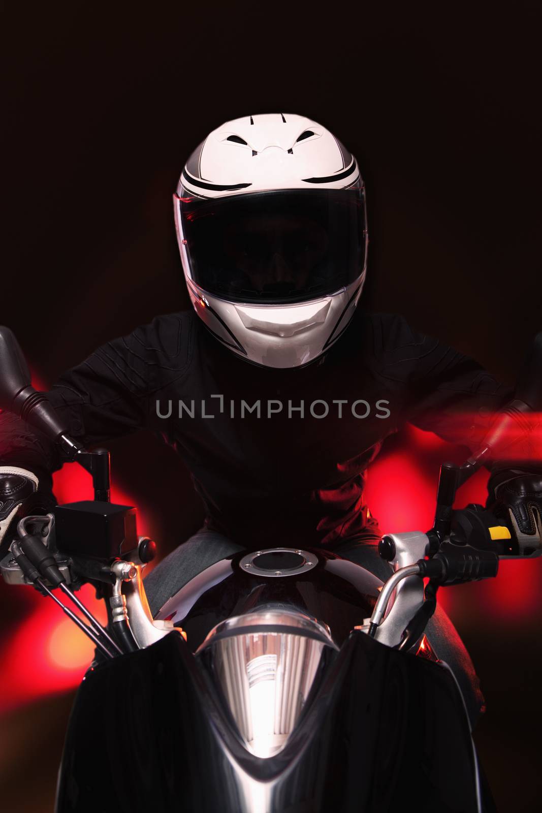 Young man riding a motorcycle at night through the streets of Beijing, front view