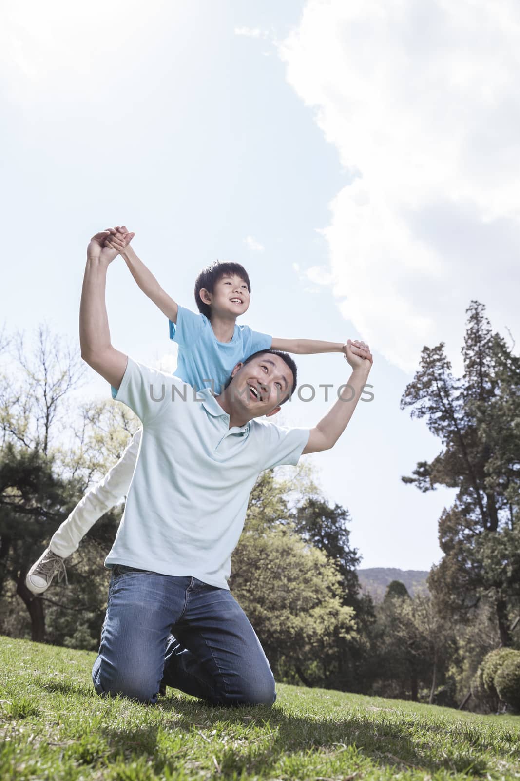 Father playing with son in park. by XiXinXing