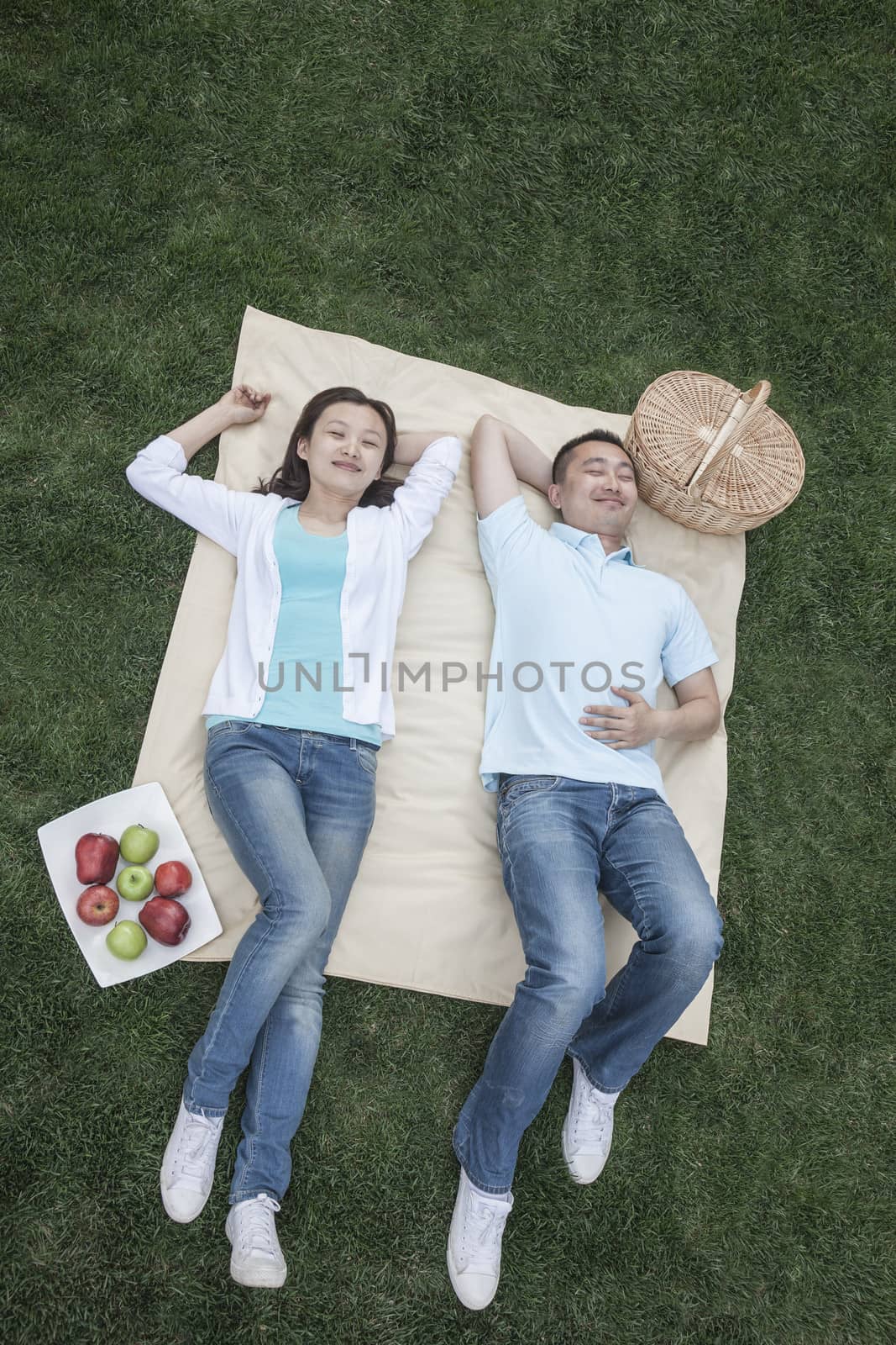 Couple lying on picnic blanket. by XiXinXing