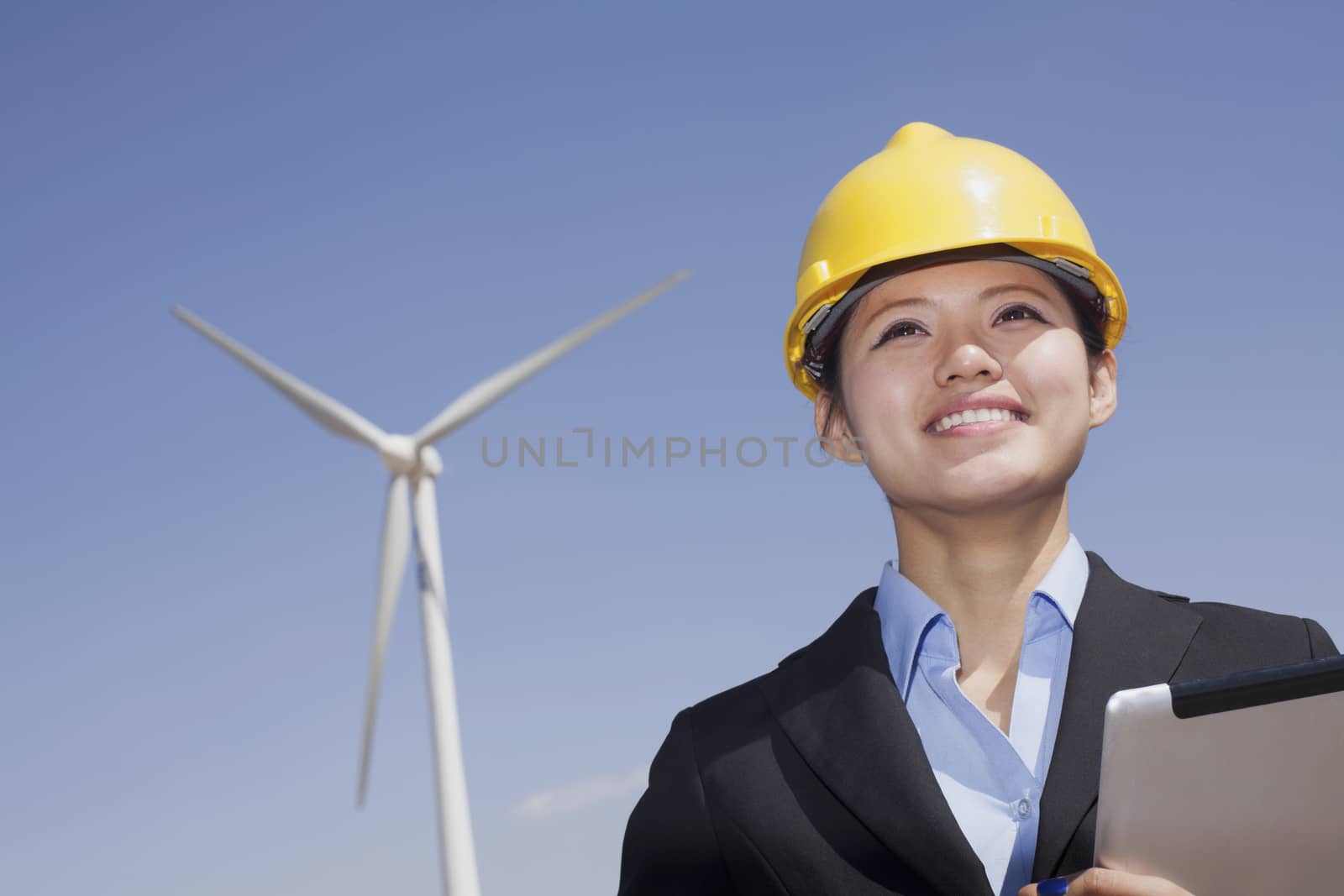 Young smiling female engineer checking wind turbines on site