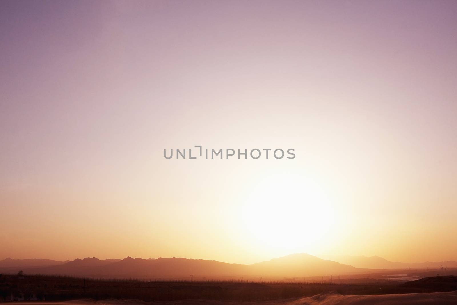 Landscape shot of sun coming down over the mountains in the desert, clear sky, China by XiXinXing