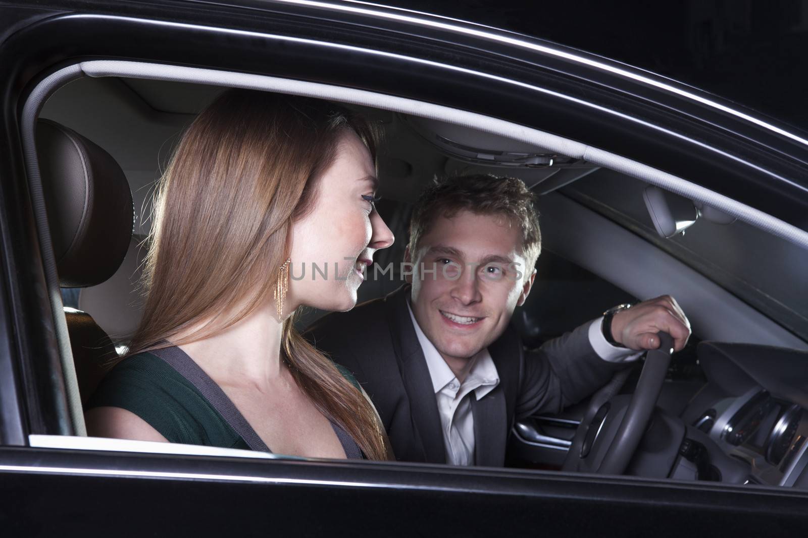 Young smiling, happy, couple sitting in their car and arriving at a red carpet event at night in Beijing by XiXinXing