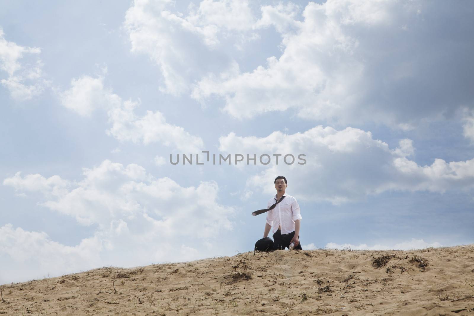 Young businessman lost and walking through the desert, distant 
