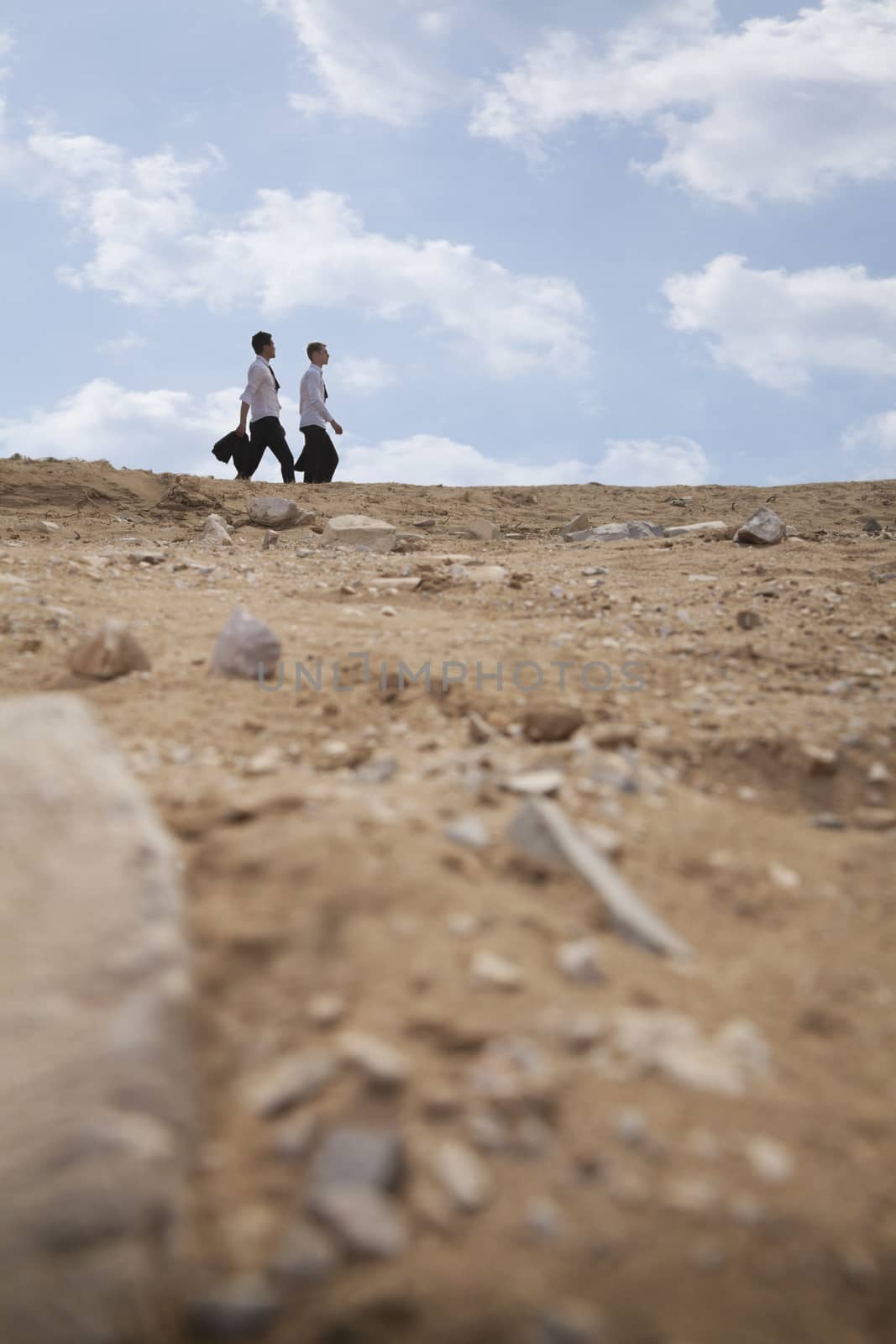 Two young businessmen walking through the desert, in the distance by XiXinXing