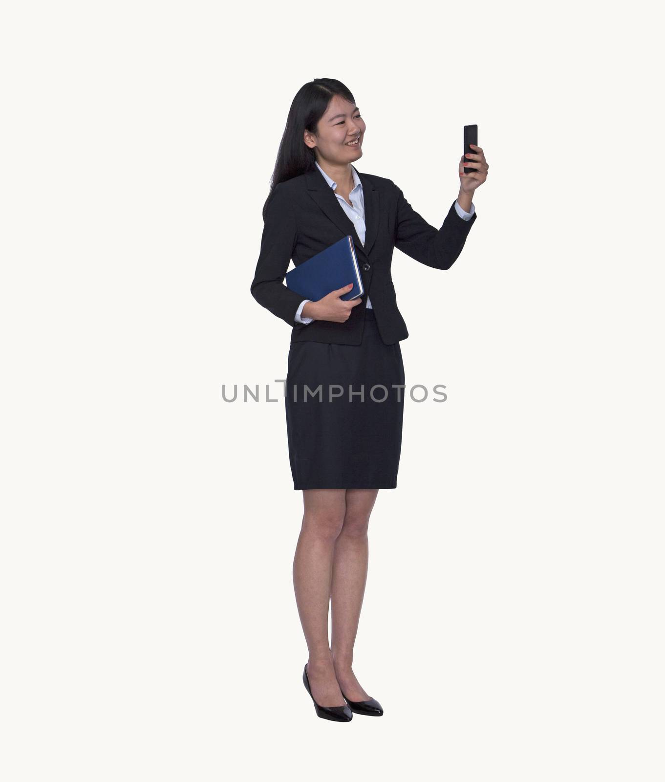 Smiling young businesswoman looking at her phone, full length, studio shot