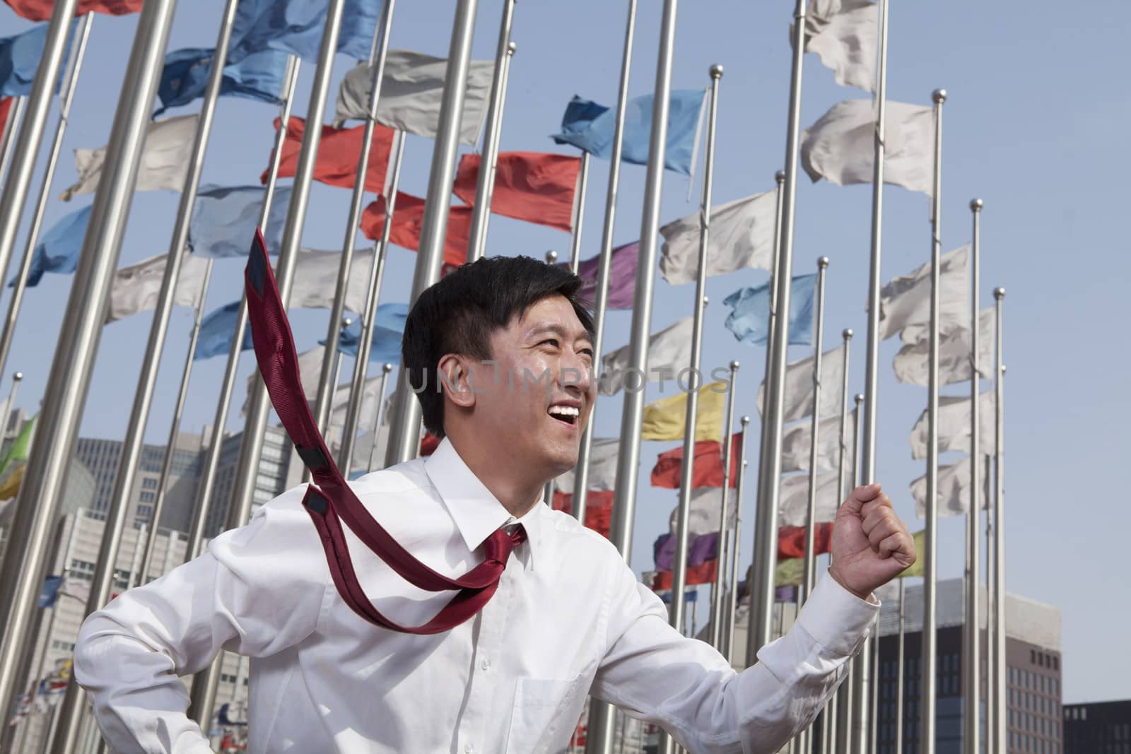 Businessmen running and smiling with flagpoles in background.