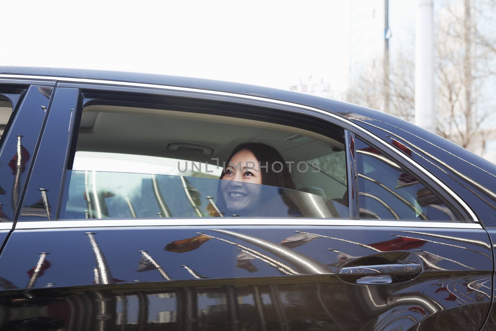 Young women in back seat of car looking out of window. by XiXinXing