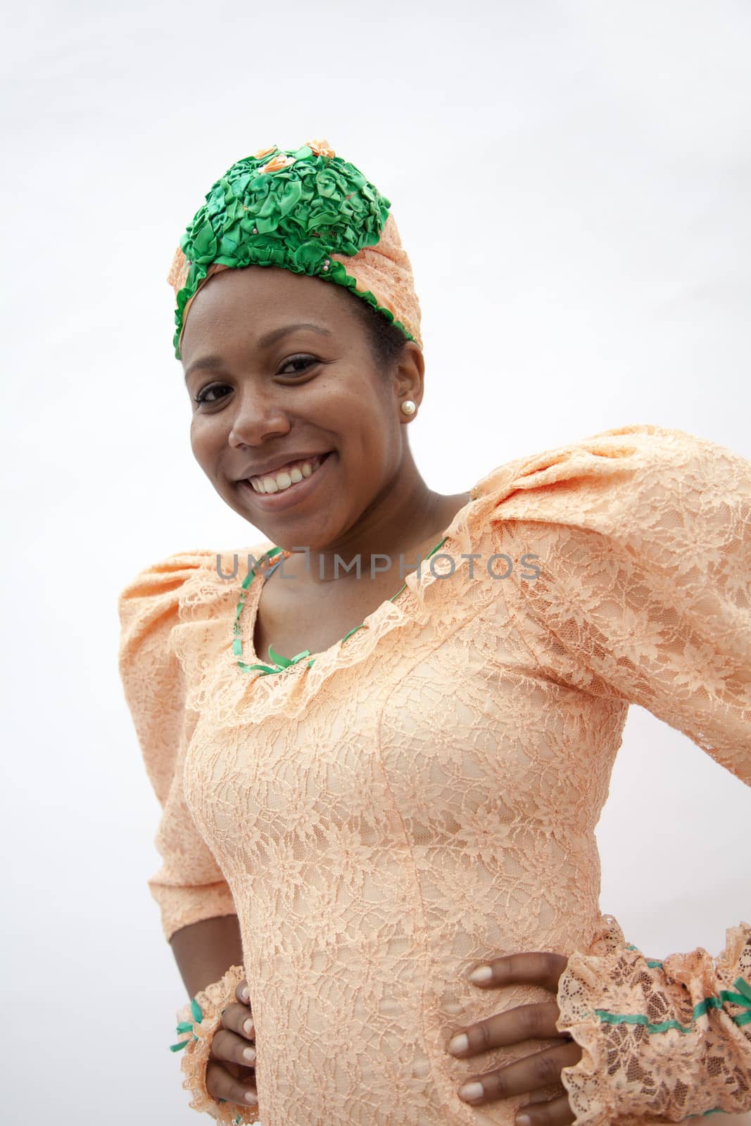 Portrait of young smiling  woman with hands on hips in traditional clothing from the Caribbean, studio shot