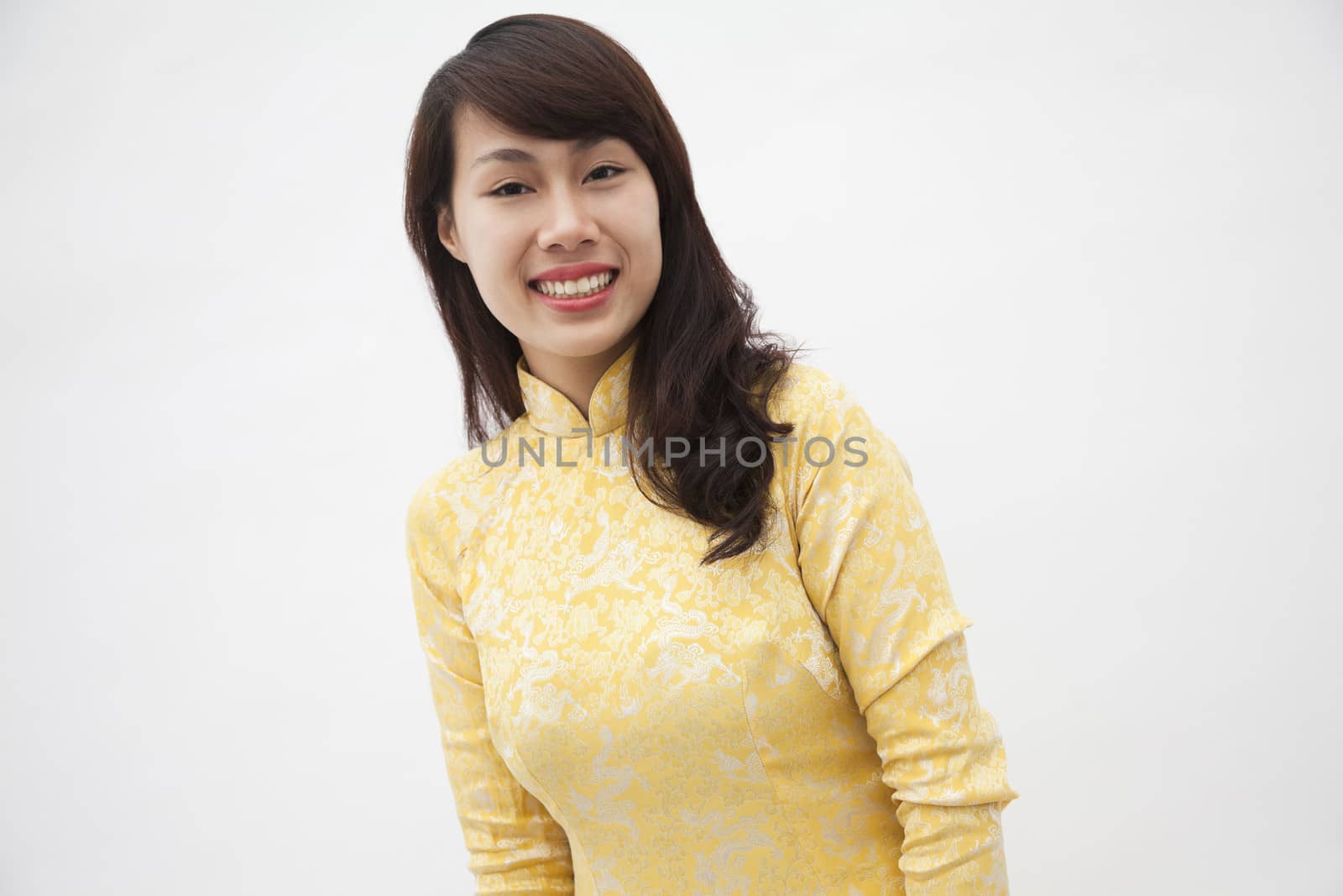Portrait of smiling young woman wearing a yellow traditional dress from Vietnam, studio shot by XiXinXing