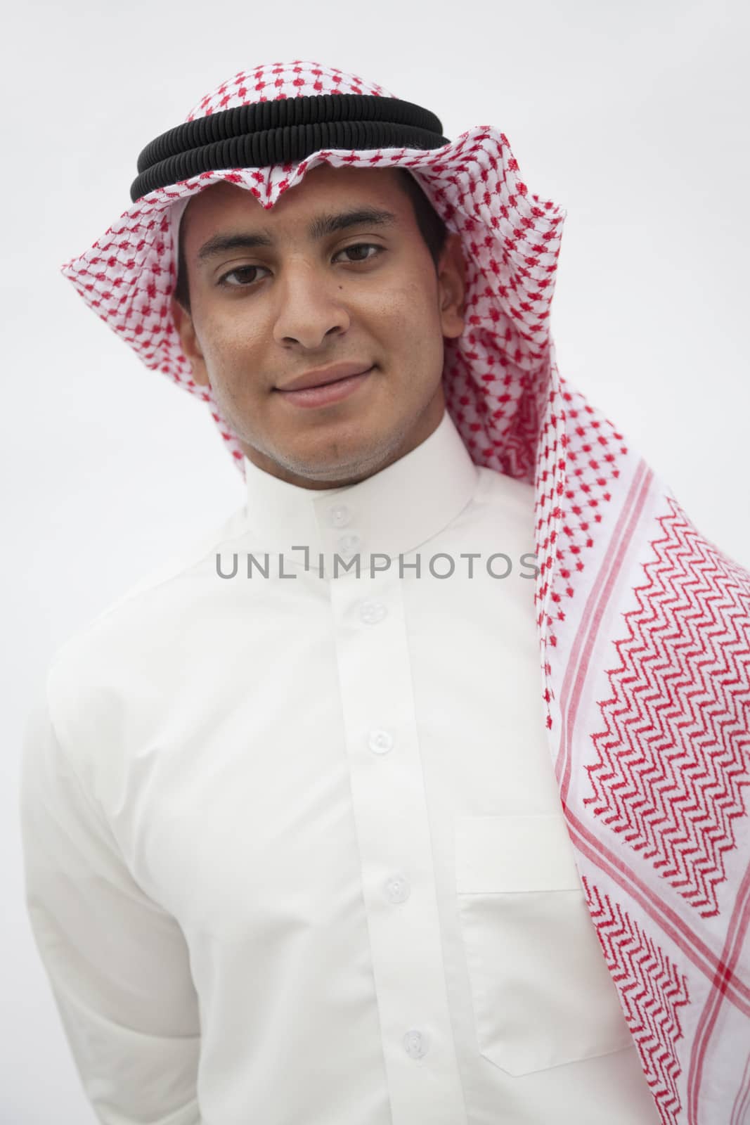 Portrait of smiling teenage boy in traditional Arab clothing, studio shot by XiXinXing