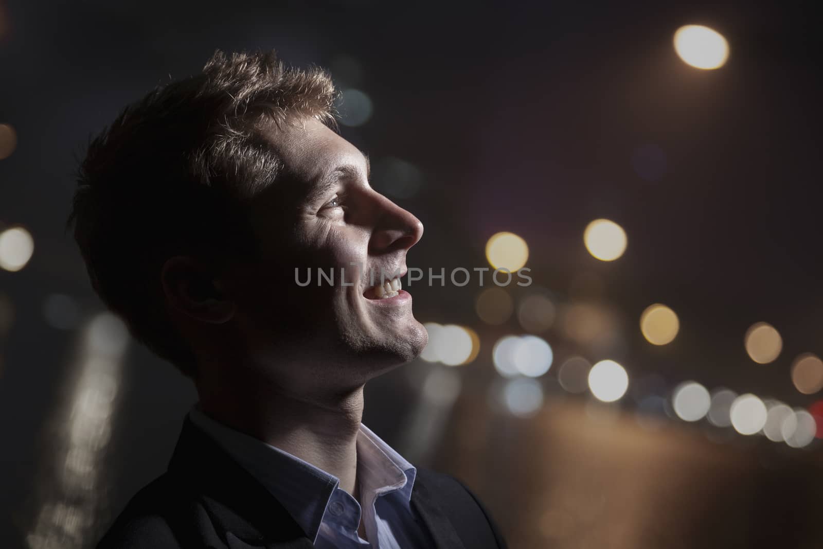 Portrait of smiling young man, profile, bright light shining on face, studio shot by XiXinXing