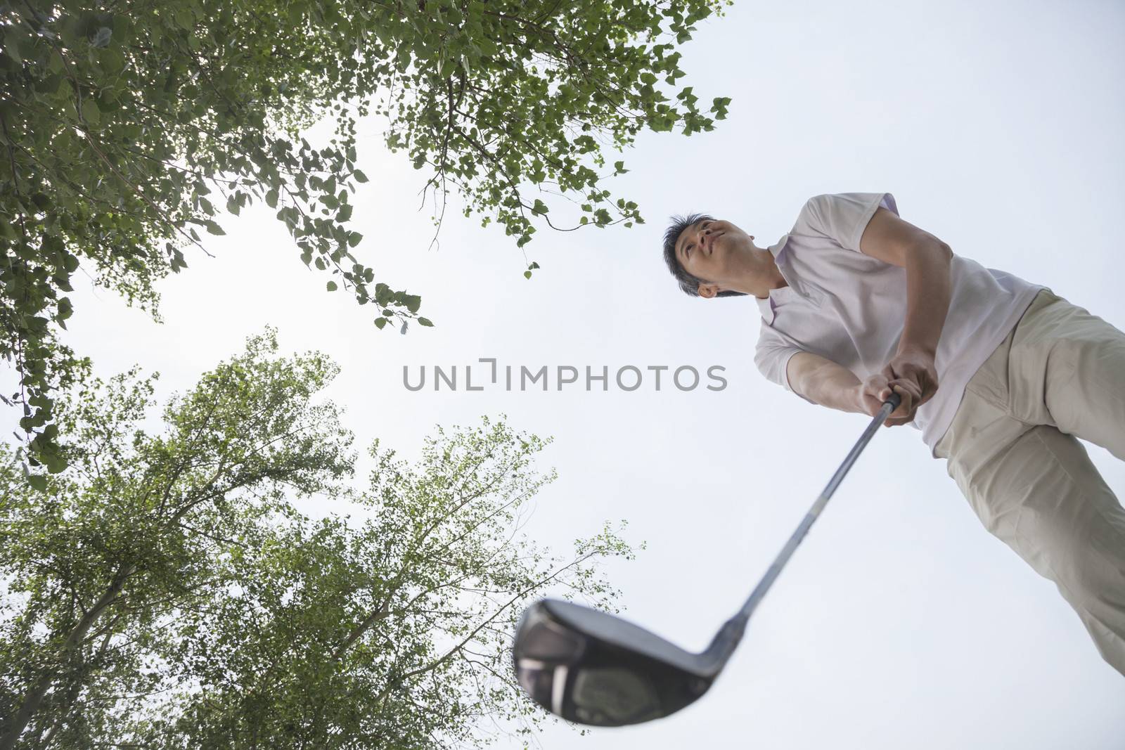 Low angle view of man getting ready to hit the golf ball on the golf course