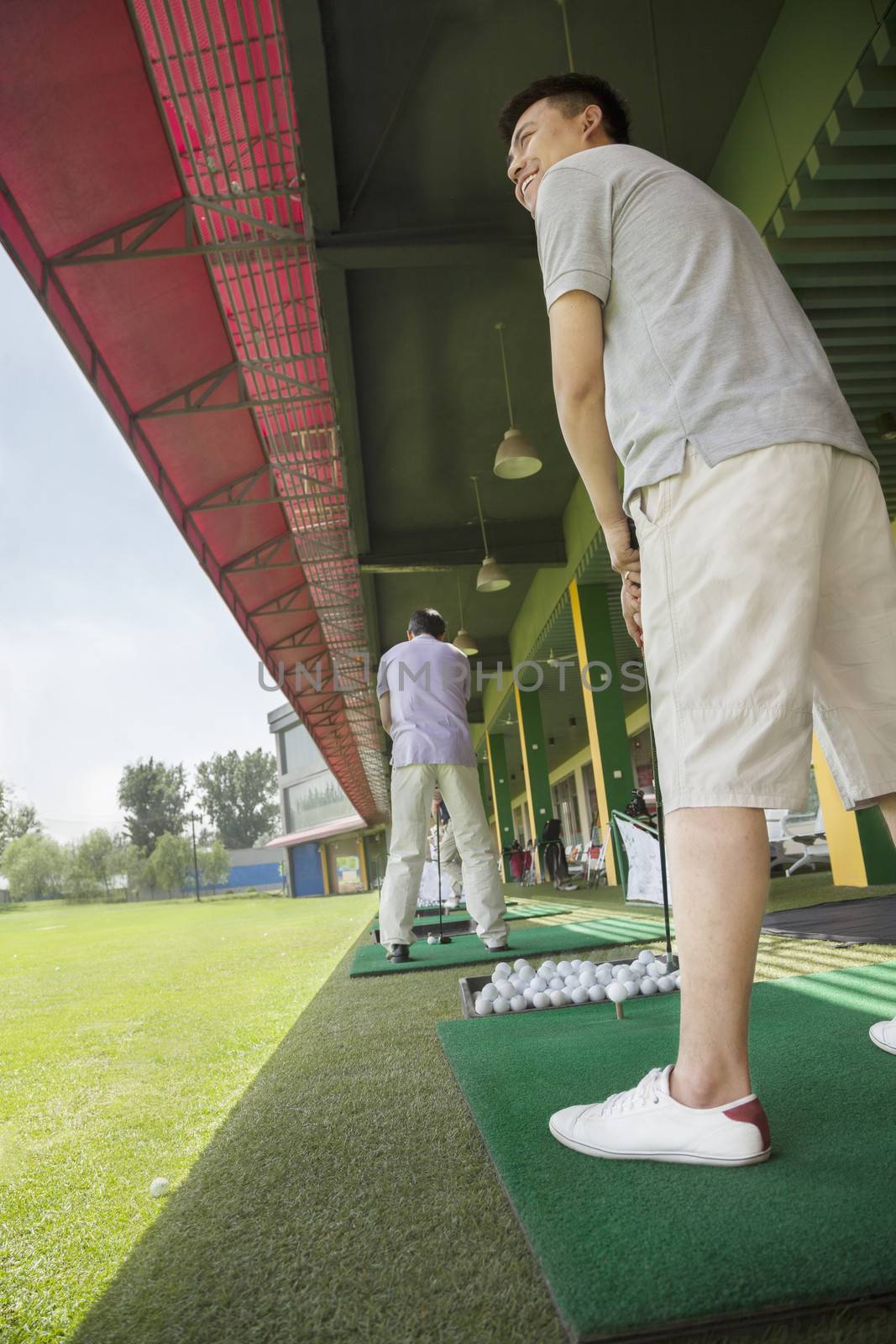 Young man swinging and hitting golf balls on the golf course