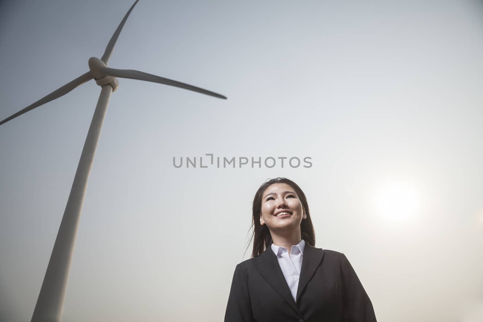 Portrait of smiling young businesswoman standing by a wind turbine