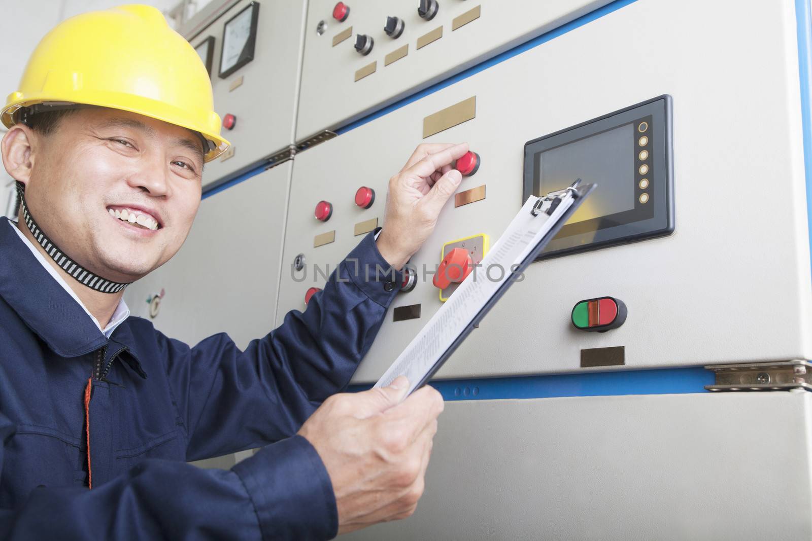 Portrait of smiling worker holding clipboard and checking controls in a gas plant, Beijing, China