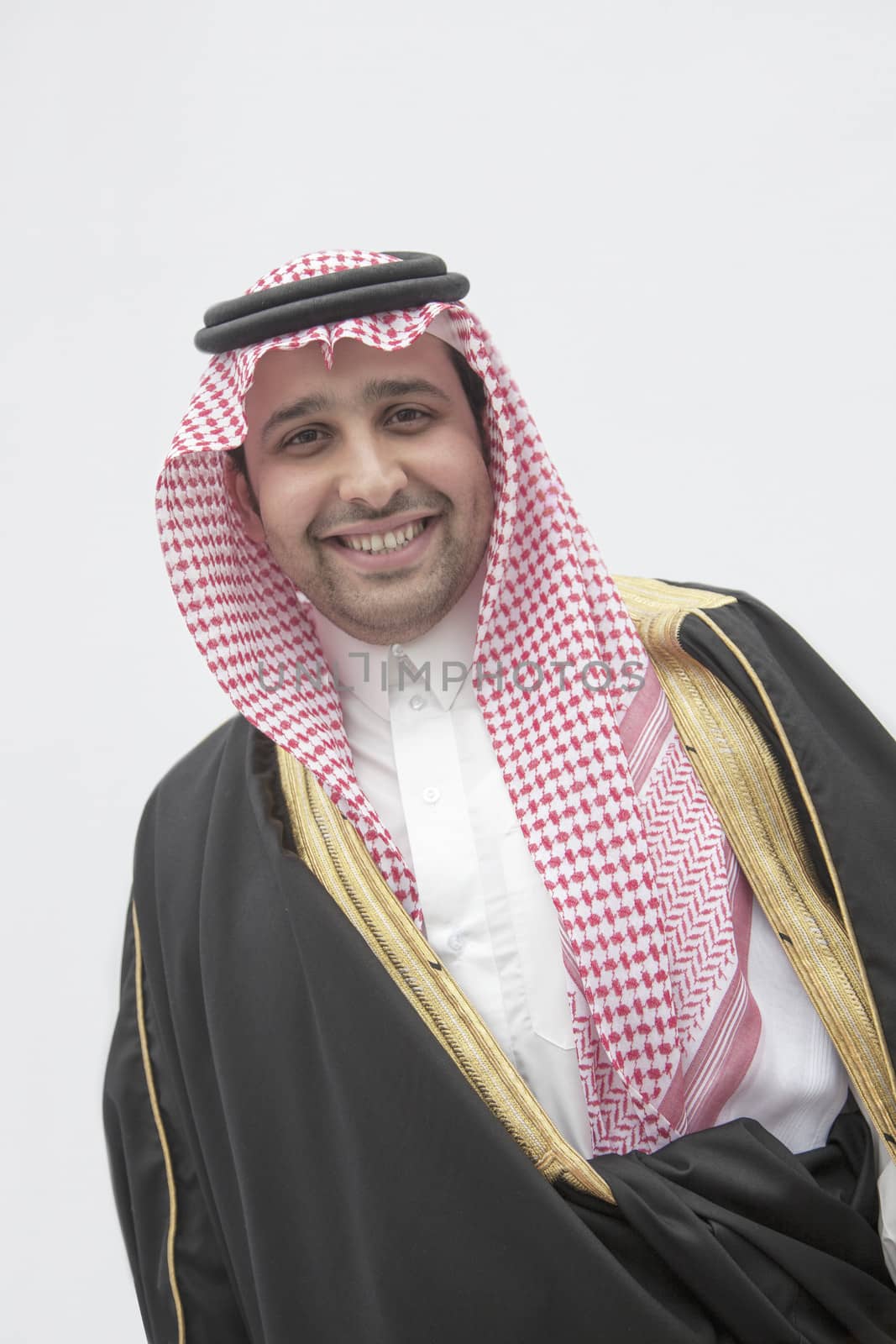 Portrait of smiling young man in traditional Arab clothing and Kaffiyeh, studio shot