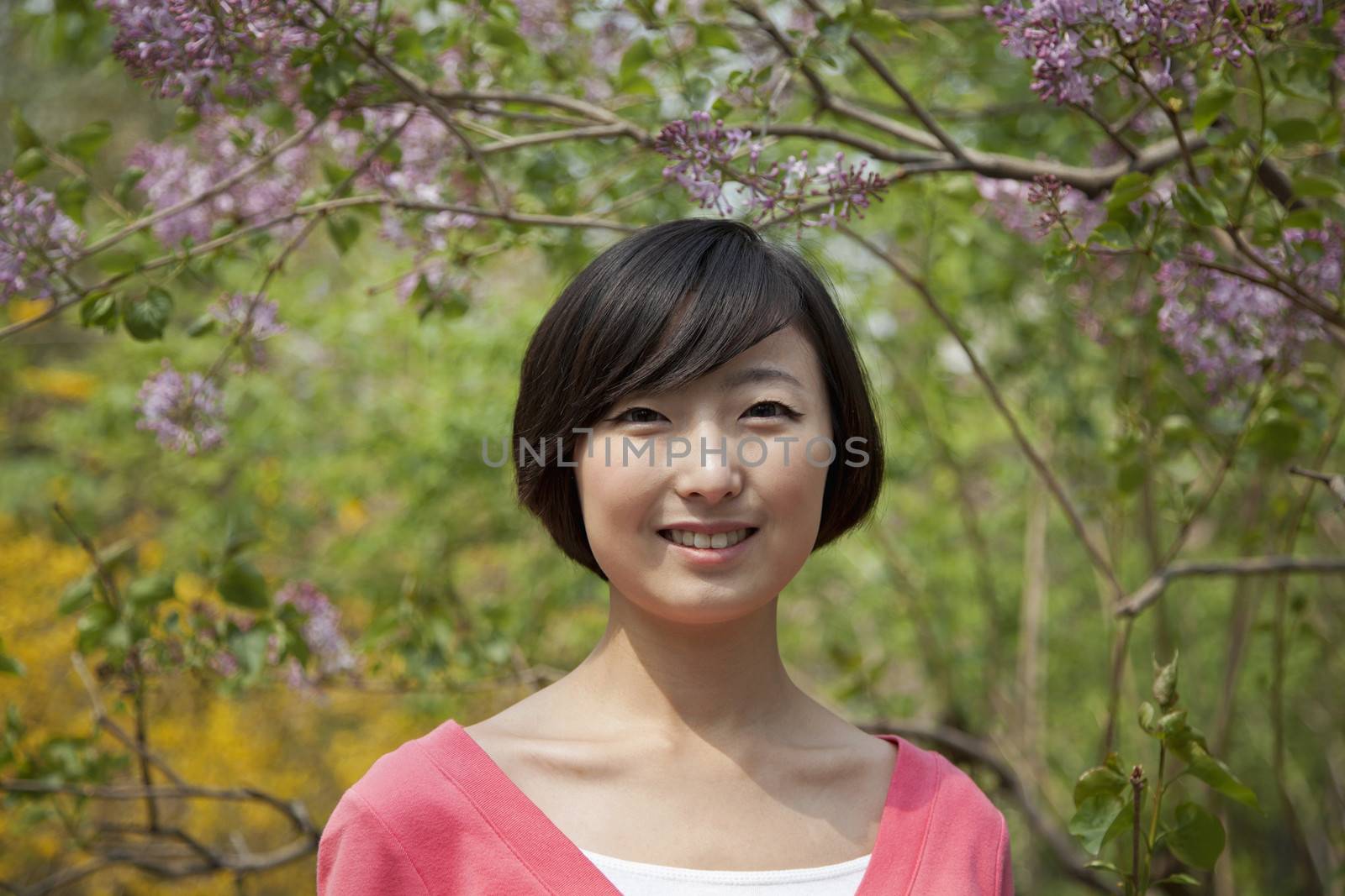 Portrait of smiling young woman with medium length hair outdoors in the park in springtime