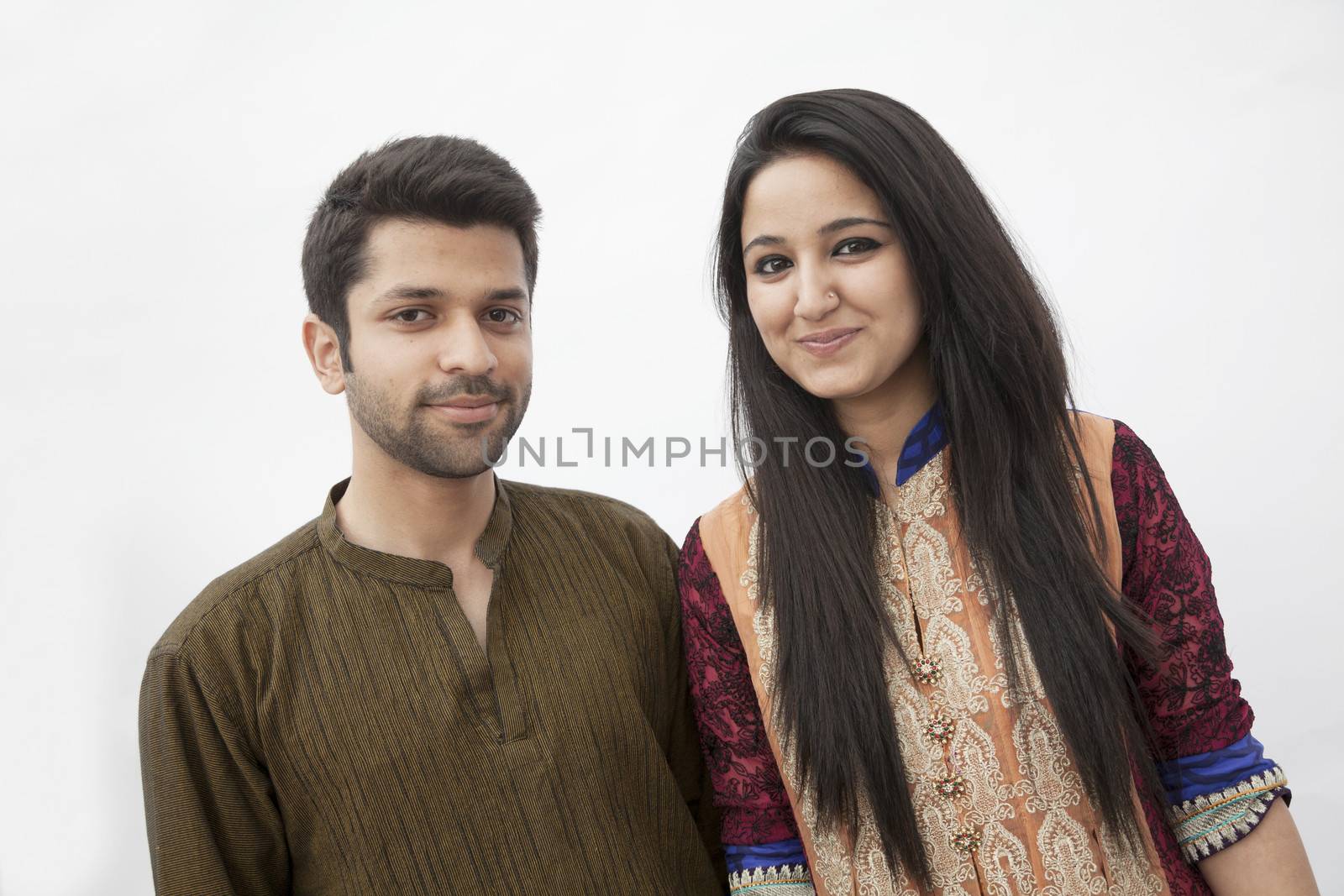 Portrait of smiling young couple wearing traditional clothing from Pakistan, studio shot
