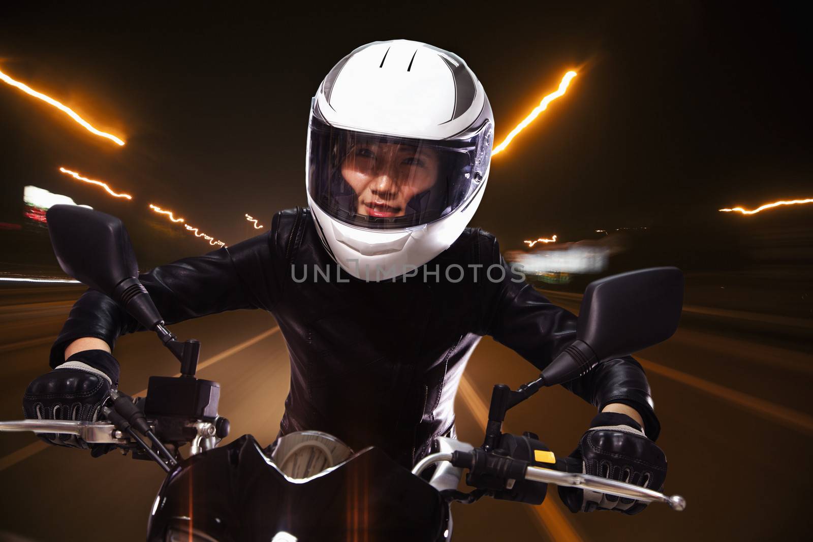 Young woman riding a motorcycle through the streets of Beijing, light trails 