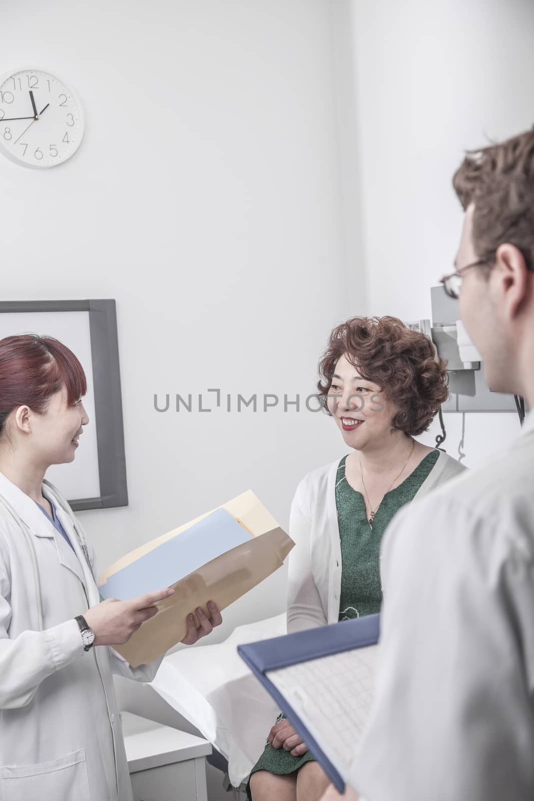Two doctors holding medical charts discussing with a patient