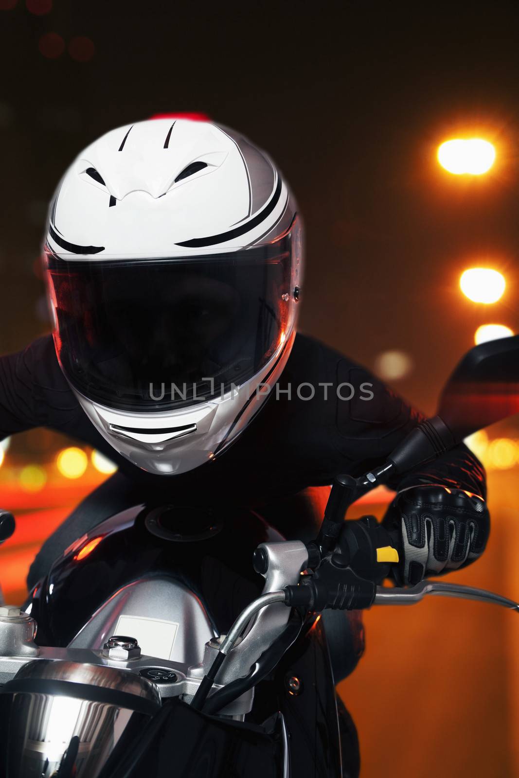 Young man riding a motorcycle at night through the streets of Beijing, front view