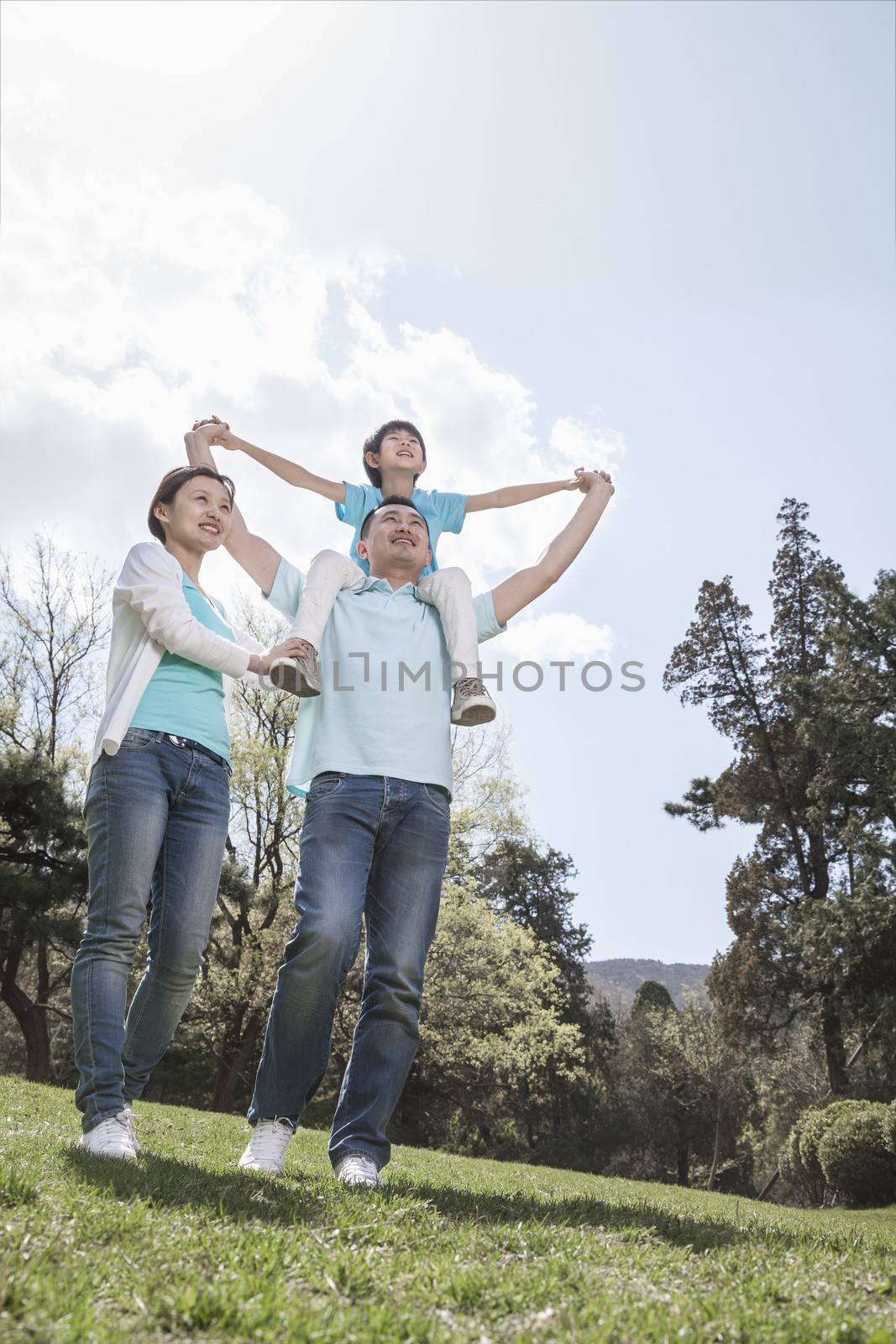 Family in park with son on father's shoulders. 