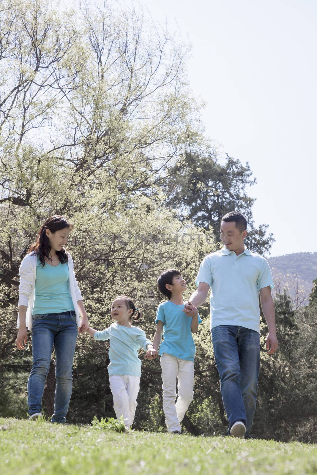 Family holding hands, walking in park. by XiXinXing