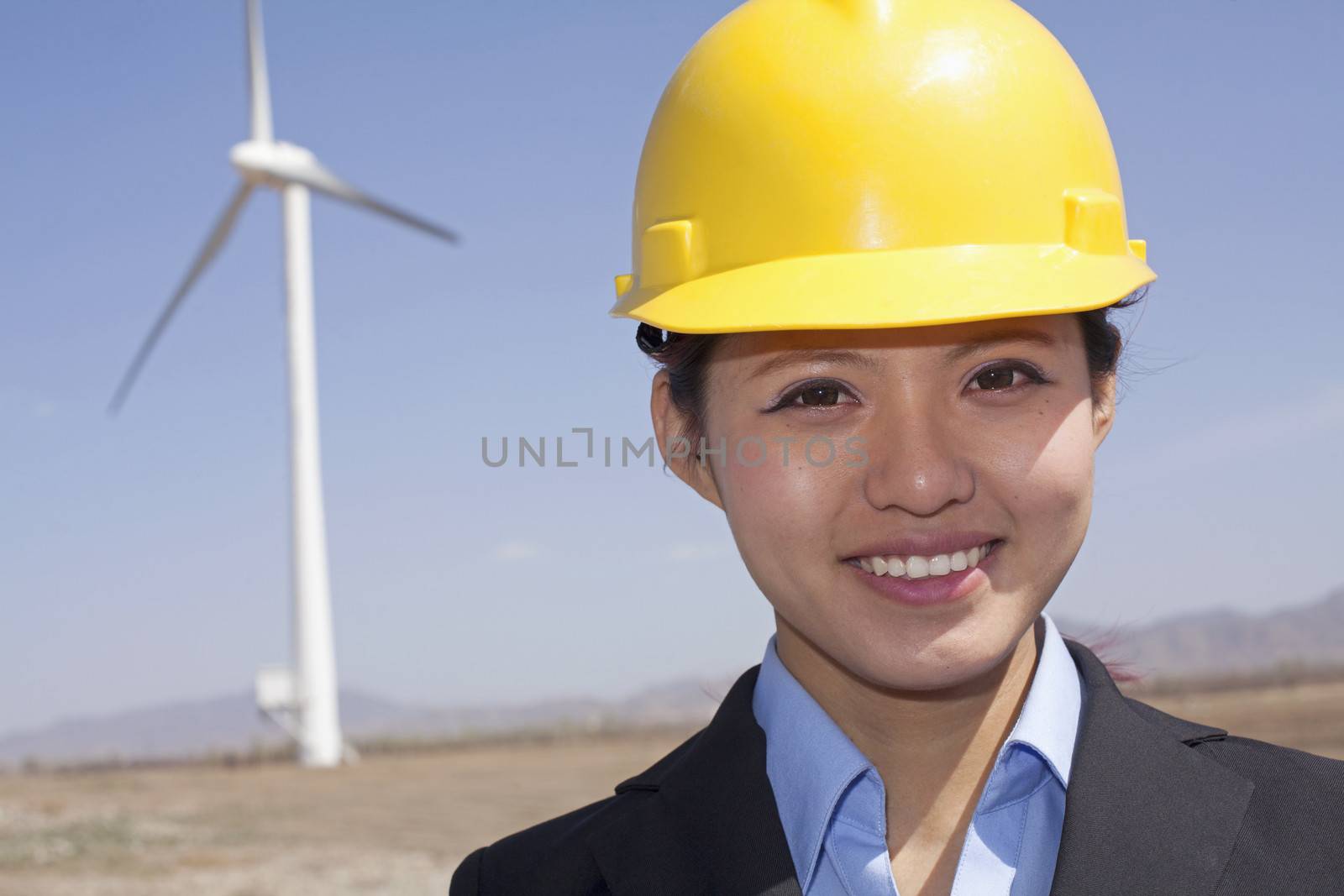 Portrait of young smiling female engineer checking wind turbines on site