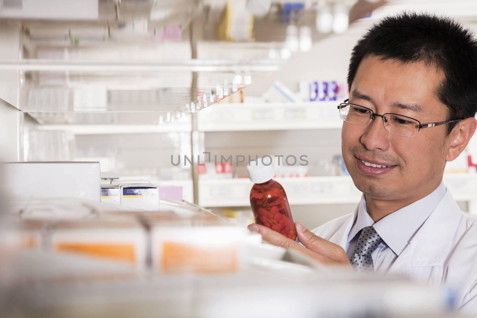 Pharmacist taking down and examining prescription medication in a pharmacy by XiXinXing