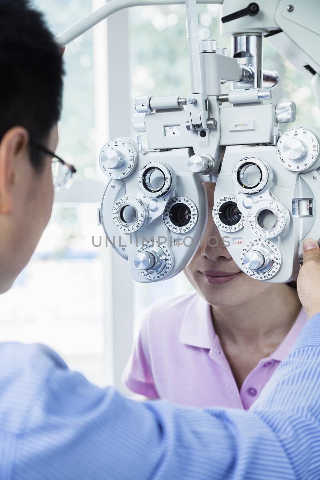 Optometrist doing an eye exam on young woman by XiXinXing