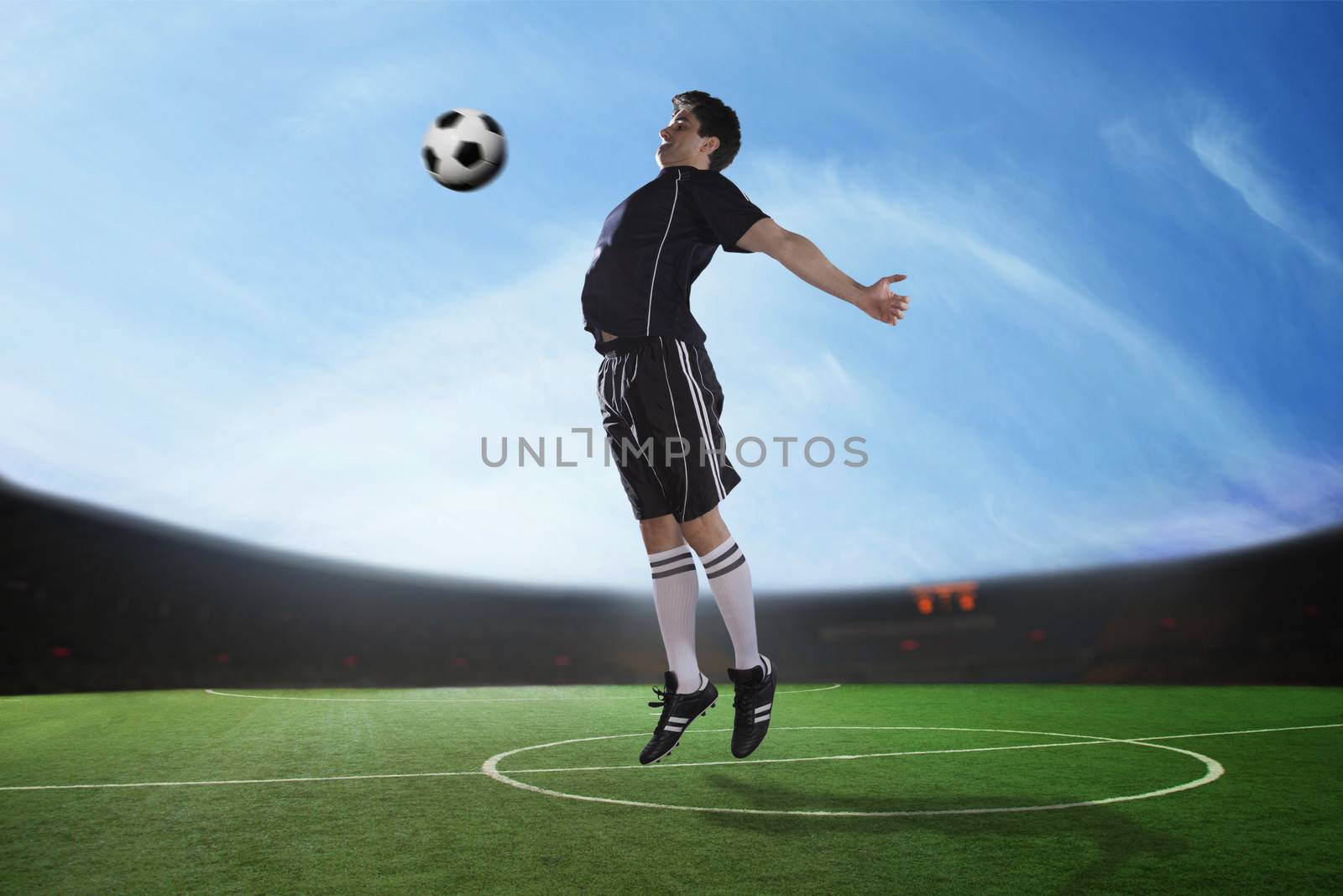 Soccer player hitting the ball with his chest in the stadium, day time