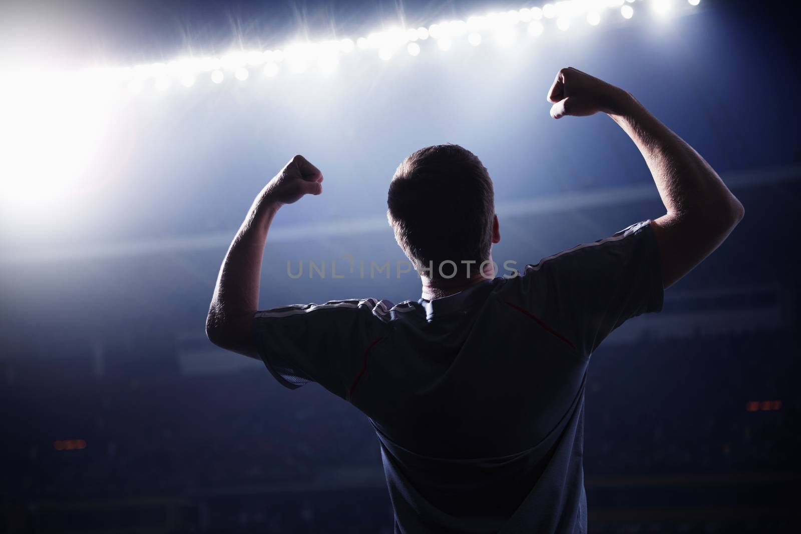 Soccer player with arms raised cheering, stadium at night time by XiXinXing