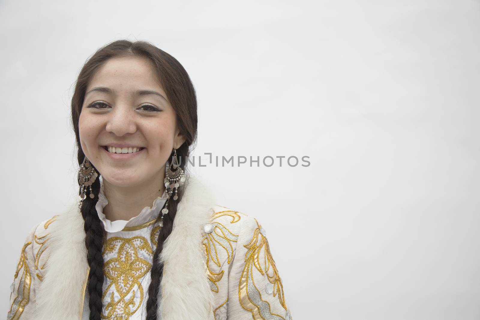 Portrait of young smiling woman with braids in traditional clothing from Kazakhstan, studio shot by XiXinXing